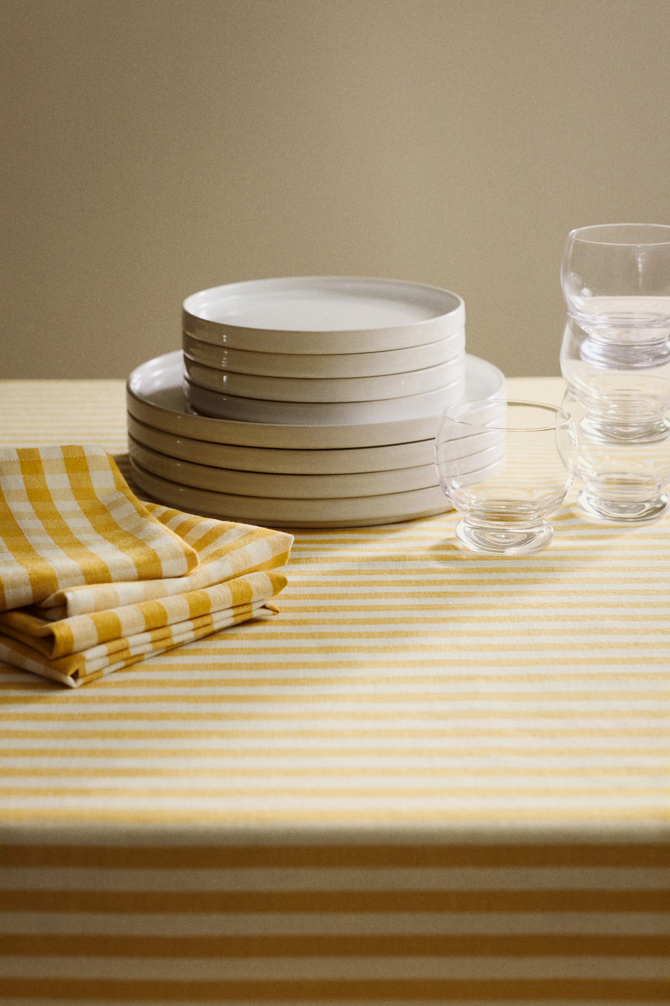 Voir une image plus grande: Une nappe classique, en tissage à motifs et fabriquée à partir d'un mélange de lin et de coton, recouvre une surface et présente des rayures horizontales alternant jaune et blanc cassé.