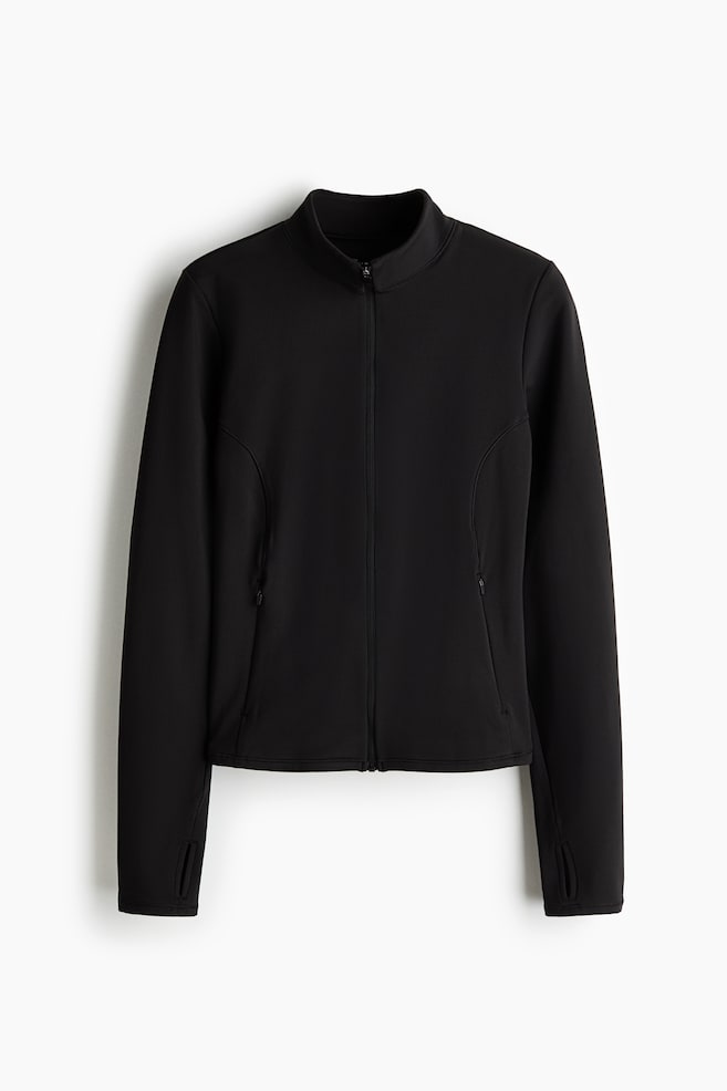 Eine schwarze Trainingsjacke ist von vorne zu sehen und zeigt einen Stehkragen, einen durchgehenden FrontreiÃverschluss sowie lange Ãrmel mit integrierten DaumenschlaufenbÃ¼ndchen. Sie verfÃ¼gt Ã¼ber geschwungene NÃ¤hte entlang des vorderen Torso mit dezenten Seitentaschen mit ReiÃverschluss. - 1