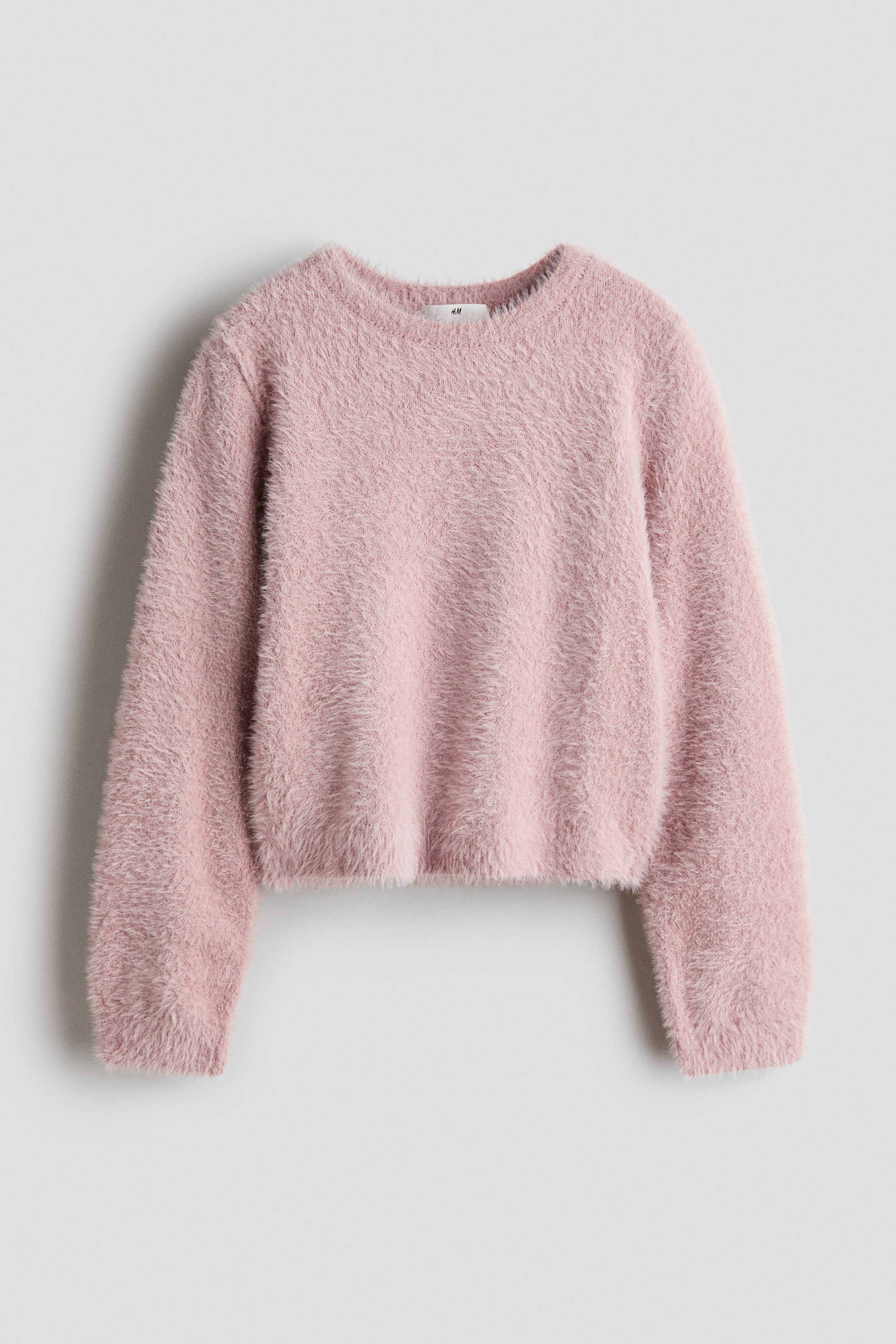 View larger image: A light pink, fuzzy knit sweater is shown from the front, featuring a round neckline, long sleeves, and a soft, textured finish.