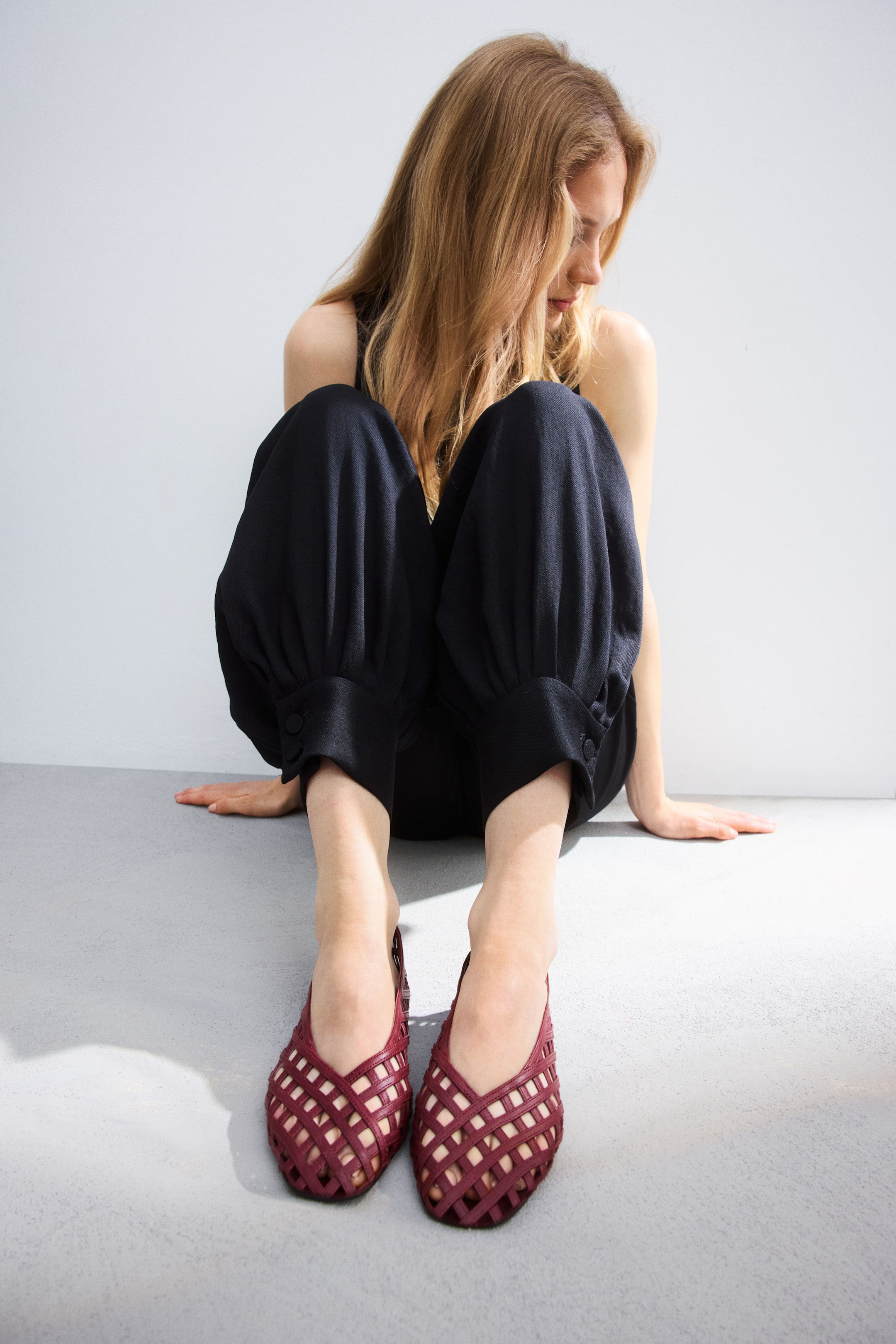 Visa större bild: Ett par vinröda vävda läder slingback flats presenteras, med skorna vinklade något framåt, vilket visar deras spetsiga tår och intrikata gallerliknande överdel.