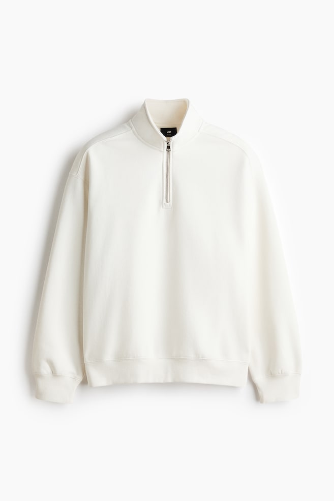 A white sweatshirt is displayed from the front, featuring a stand-up collar with a partial zip fastening. It showcases dropped shoulders, long sleeves, and ribbed cuffs and hem, creating a relaxed fit. - 1