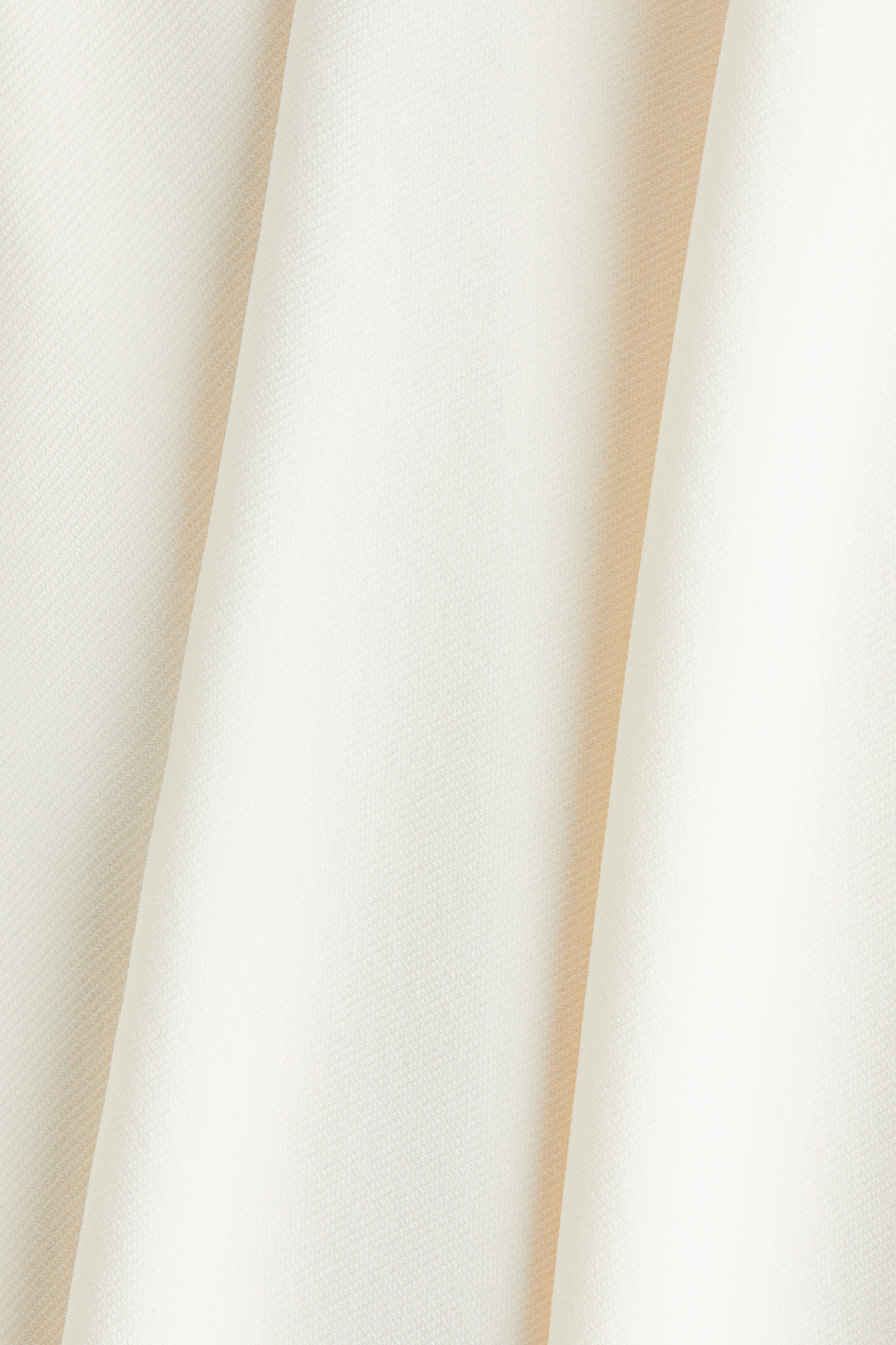 View larger image: A cream-colored fabric is displaying a subtle, finely textured weave, with soft vertical folds creating shadows.