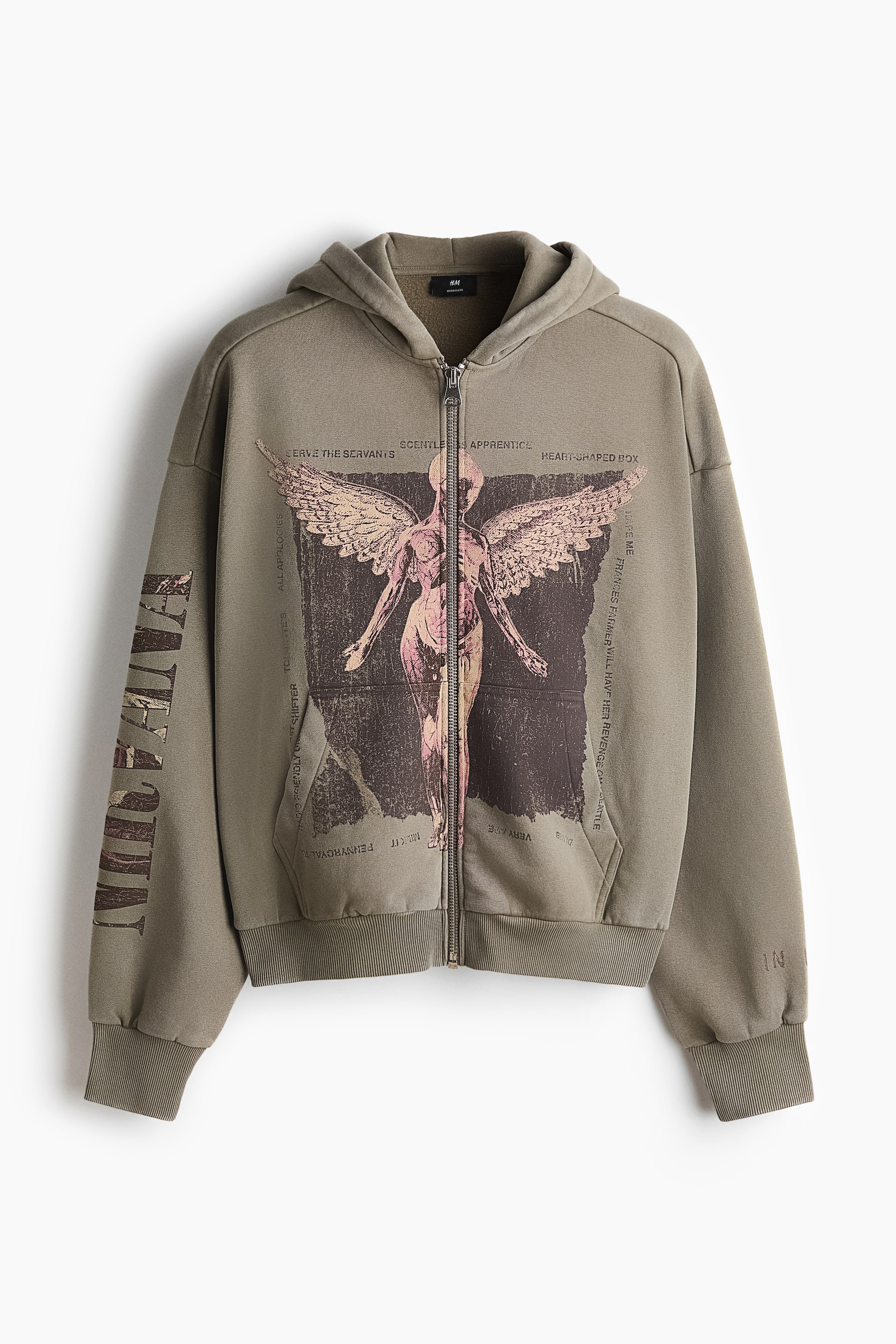 Vis større bilde: En olivengrønn hoodie med hel glidelås vises forfra, med en stor slitt grafikk av en anatomisk figur med vinger på brystet, omgitt av ulike sangtitler og tekstlinjer. Den er designet med hette, ribbestrikkede mansjetter, ribbestrikket kant nederst og lommer foran, med «Nirvana» trykt vertikalt på venstre erme.