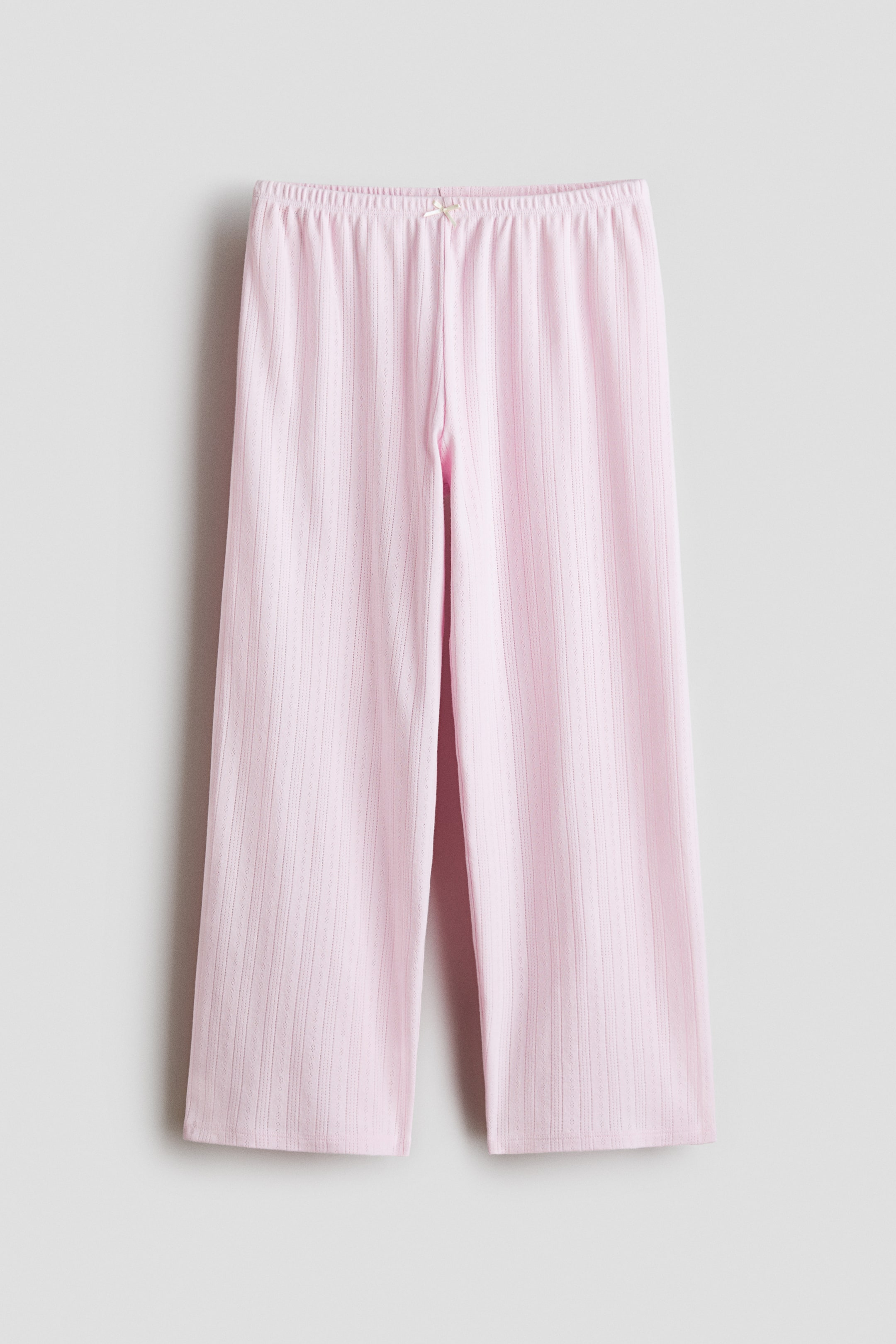 Agrandir l'image: Le pantalon en maille côtelée rose est doté d'une taille élastiquée agrémentée d'un petit nœud à l'avant. Il adopte une coupe droite à jambes larges.