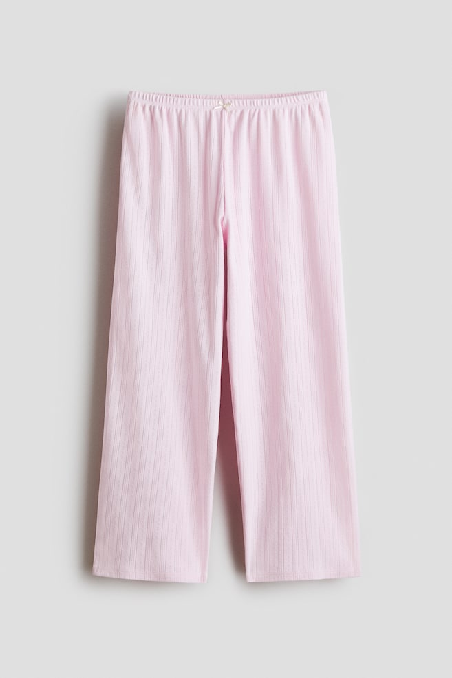 Roze ribgebreide broek is voorzien van een elastische tailleband met een klein strikje aan de voorkant. De broek heeft een rechte, wijdvallende pasvorm. - 1