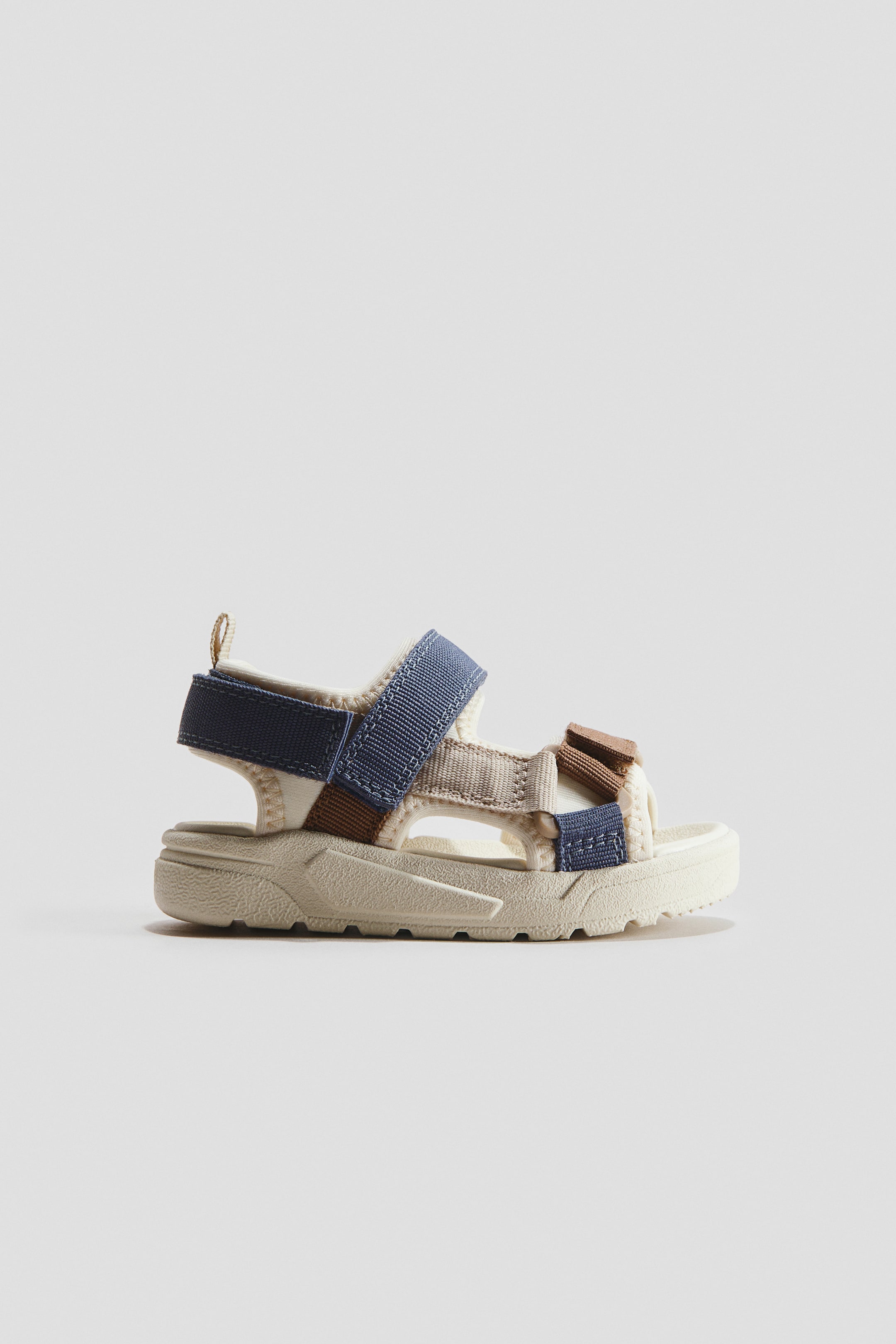 View larger image: The sandals are shown in a side profile, crafted from scuba fabric with adjustable multicolored grosgrain straps. The straps fasten with hook-and-loop closures over the foot and around the ankle. The sandals feature molded insoles and fluted soles.