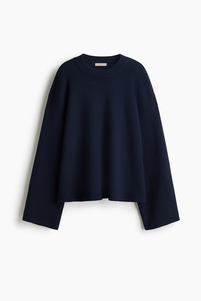 An oversized, dark blue jumper is presented from the FRONT, featuring a soft, fine knit. It is designed with a ribbed crew neck and long, gently flared sleeves, ending with a straight hem. - 1