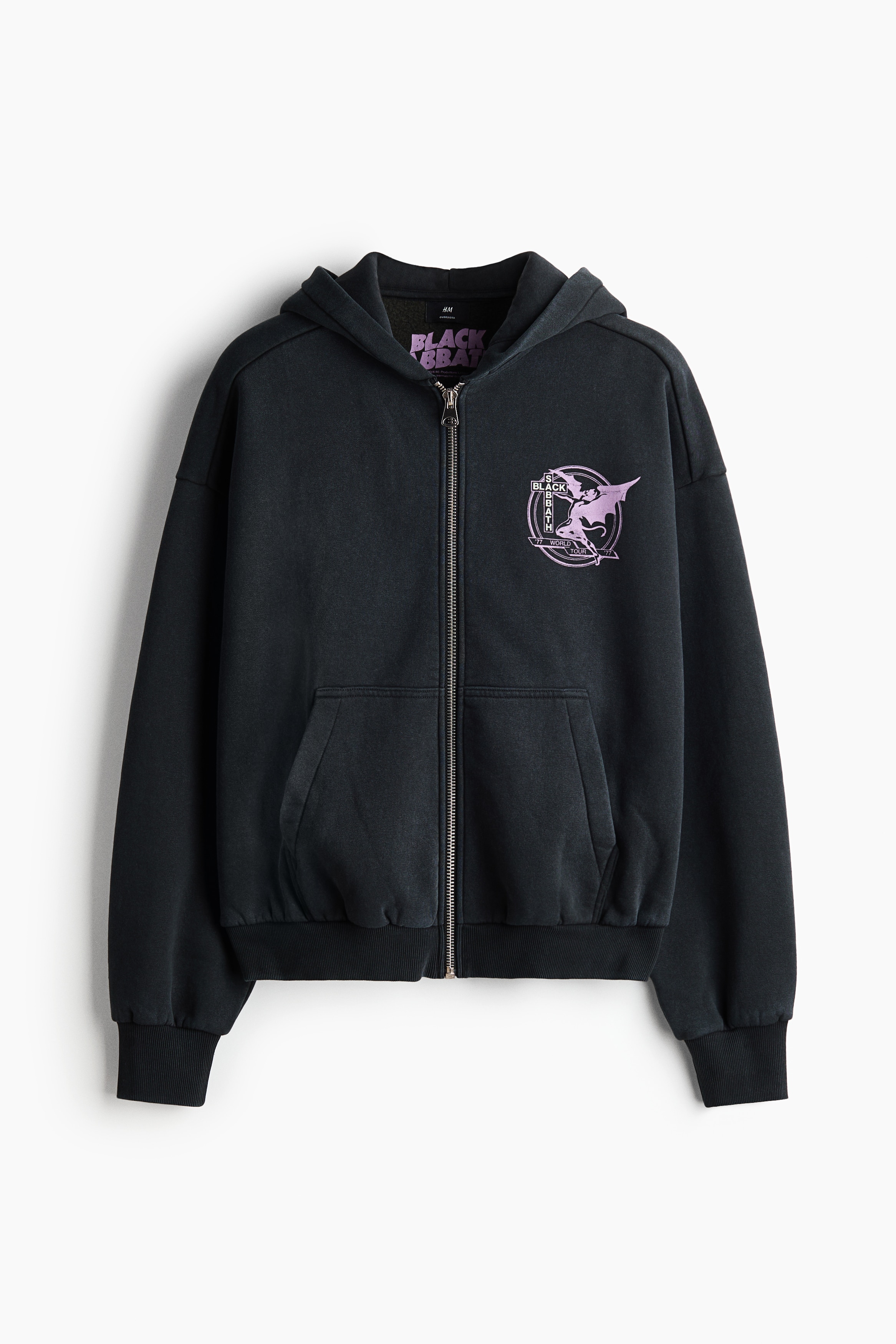 A black oversized hoodie featuring a white "BLACK SABBATH WORLD TOUR '77" graphic print on the back is being worn by the model, who is viewed from behind. The model is adjusting the hood with both hands, showcasing the relaxed fit, dropped shoulders, and ribbed cuffs of the garment.