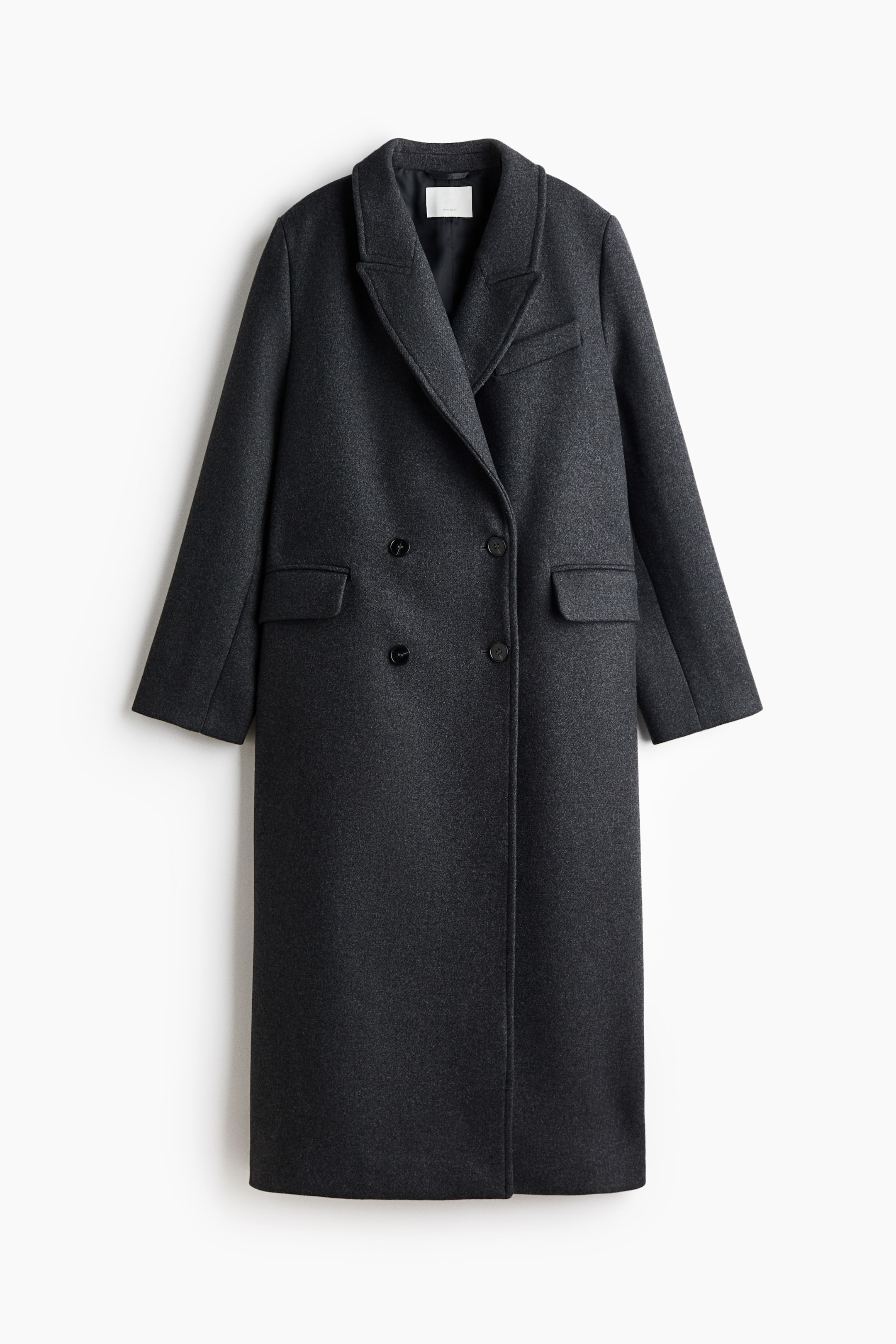 Visualizza immagine più grande: Questo lungo cappotto doppiopetto in misto lana grigio scuro è appeso frontalmente e presenta revers a lancia, spalle strutturate e una silhouette dritta. Mostra una chiusura doppiopetto con bottoni, un taschino a filetto decorativo sul petto e due tasche frontali a filetto con patta.