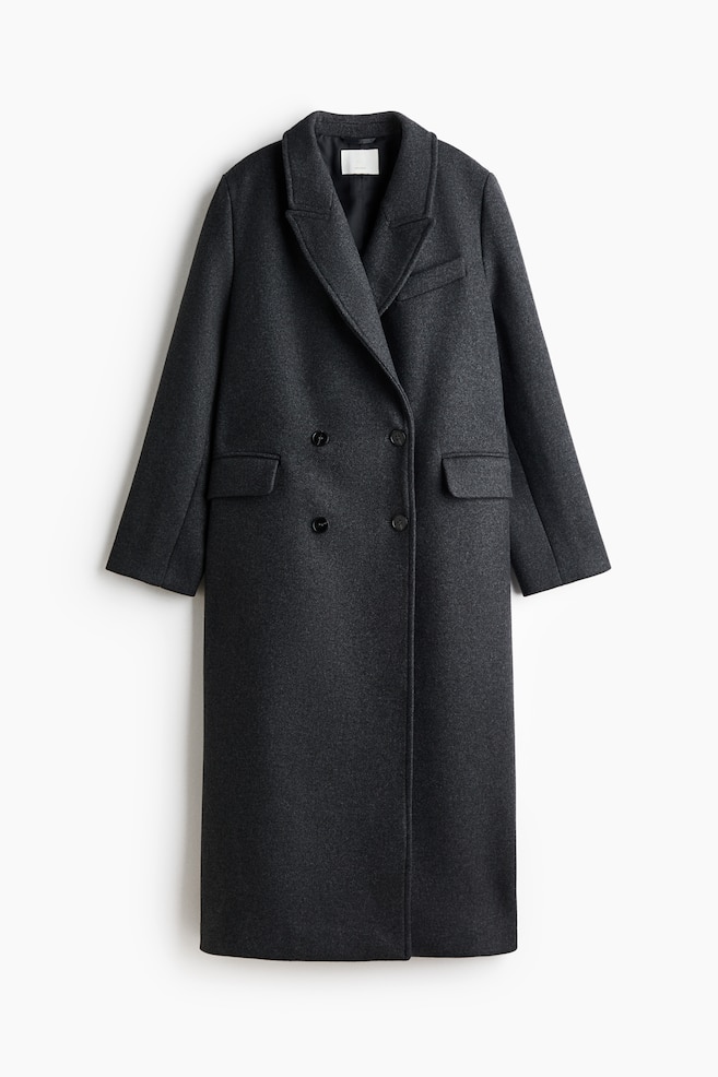 This long, double-breasted coat in a dark grey wool blend is hanging front-facing, featuring peak lapels, structured shoulders, and a straight silhouette. It is shown with a double-breasted button fastening, a decorative welt chest pocket, and two jetted front pockets with flaps. - 1