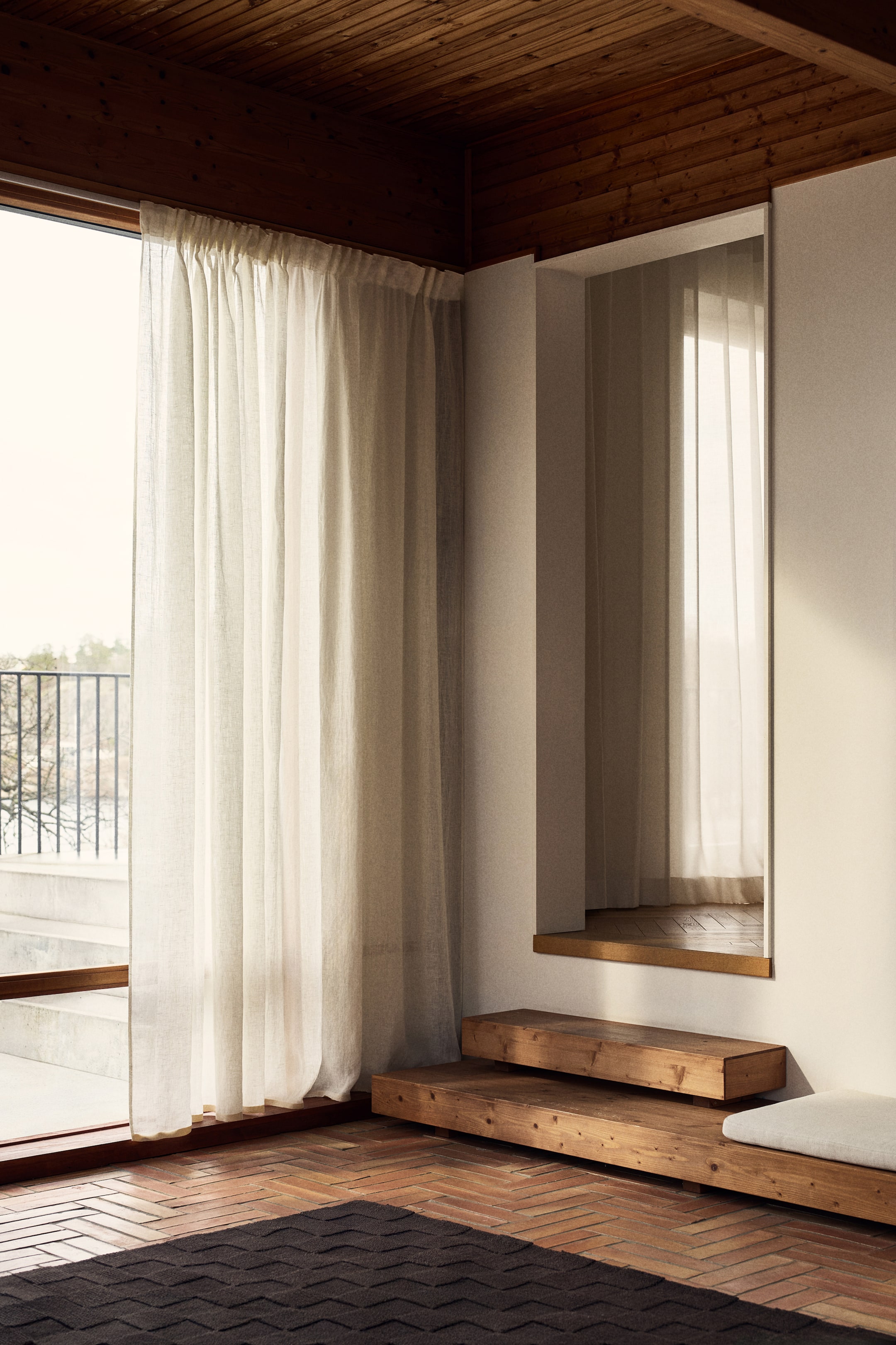 Voir une image plus grande: Un rideau transparent beige clair est suspendu, avec des plis froncés en haut et tombant jusqu'au sol, couvrant une fenêtre.