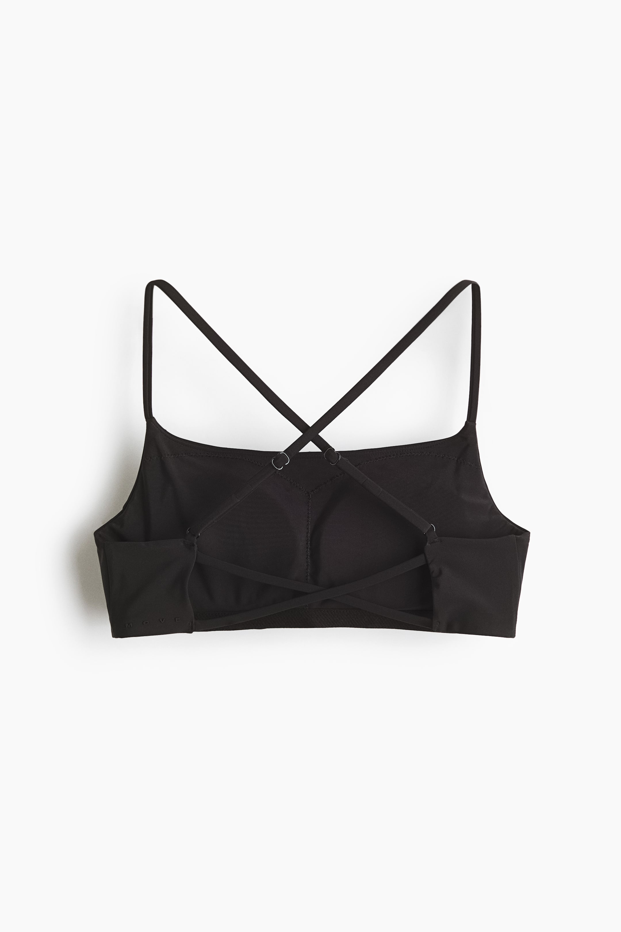View larger image: A black sports bra showcases its back, featuring thin straps crossing in an X-shape. Small rings are visible at the strap connection points, and a wider band defines the lower edge.