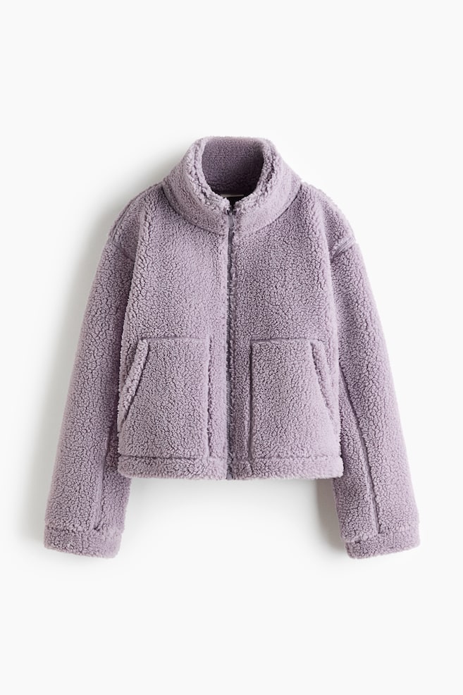 A purple sherpa fleece jacket is facing front, displaying a full-zip closure and a stand-up collar. The cropped jacket is featuring two large patch pockets on its lower front. - 1