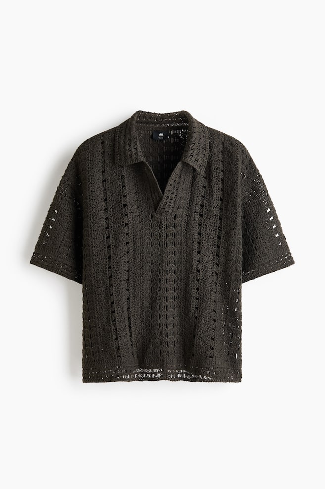 A deep green crocheted polo shirt showcases an intricate openwork knit pattern all over. It features a pointed collar, a V-neck opening, and short sleeves. - 1