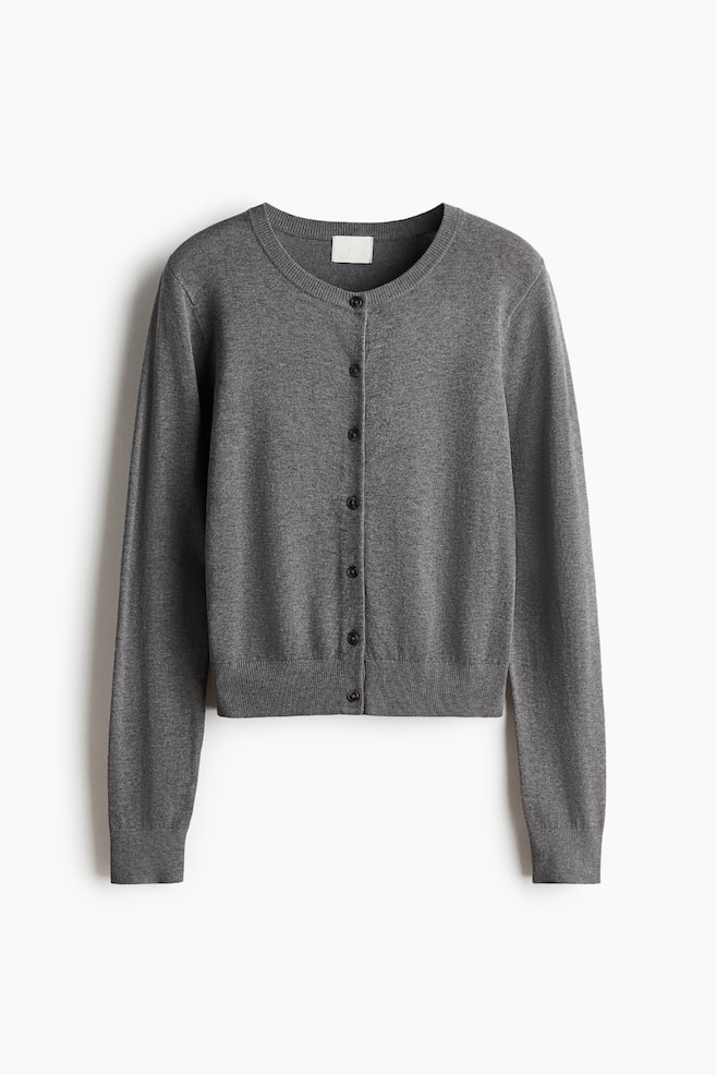 Een grijze cardigan ligt plat en naar voren gericht, met een ronde halslijn, een knopenlijst met donkere knopen in het midden, en geribbelde details aan de halslijn, manchetten en zoom. - 1