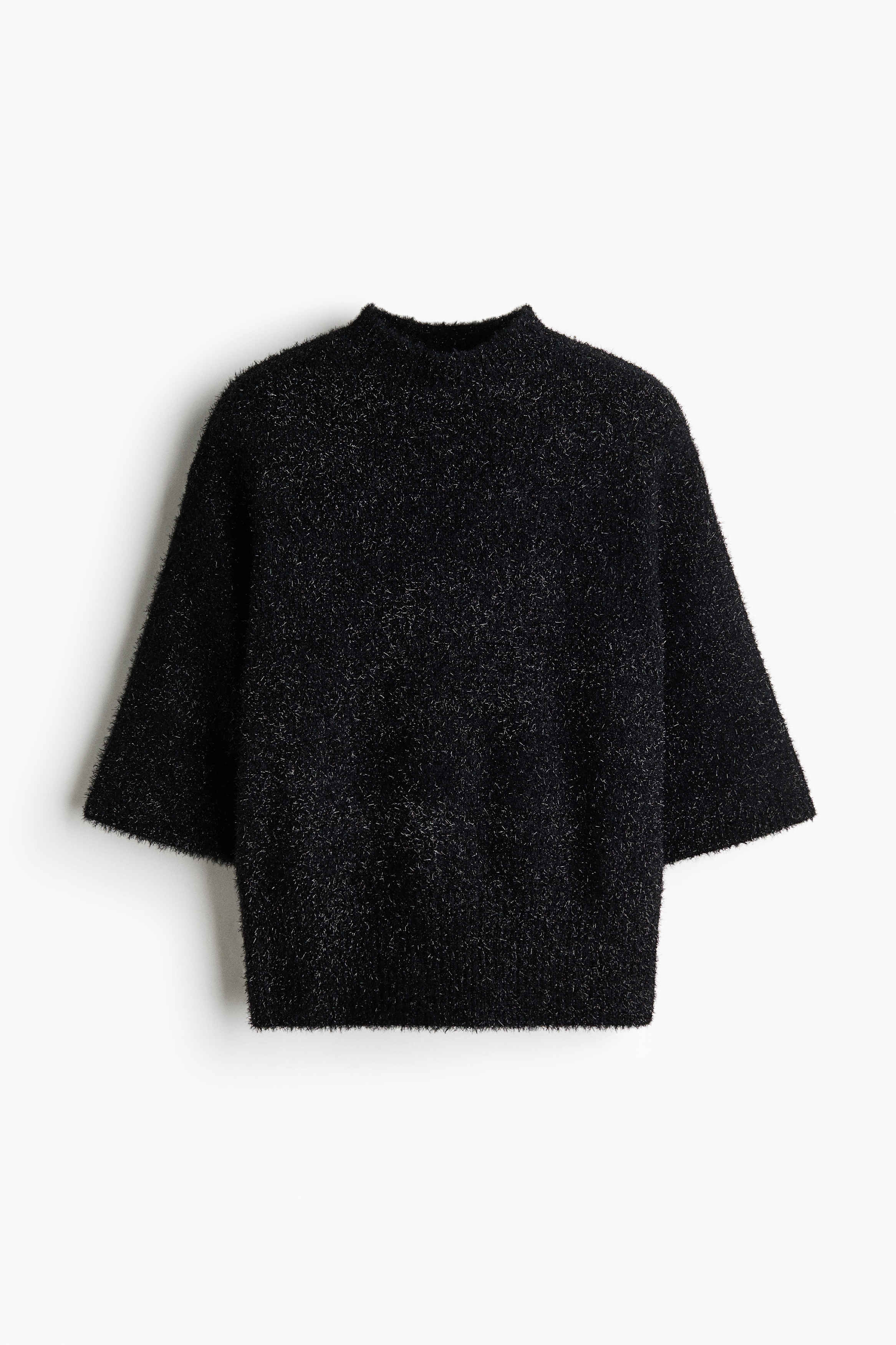 The model is wearing a black fluffy knitted top with glittery threads, featuring a ribbed roll neck, dropped shoulders and elbow-length sleeves. The top is styled with a black skirt with a front slit, and the model has one hand resting on her hip.