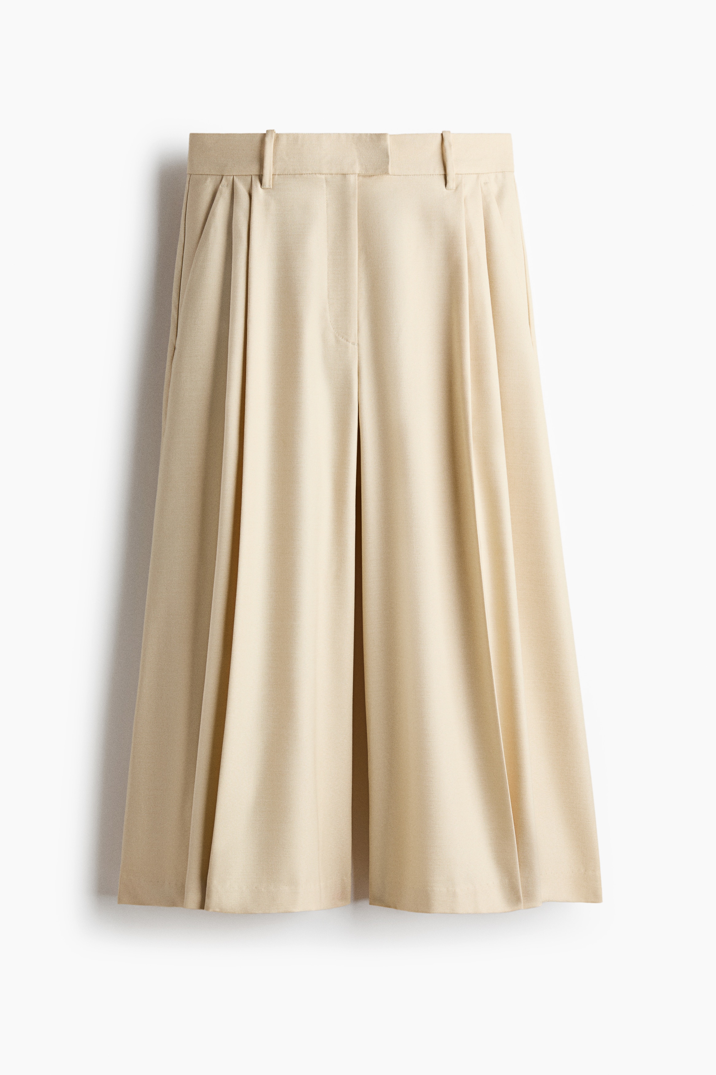 Máº«u Äang máº·c quáº§n culottes dÃ¡ng rá»ng mÃ u be nháº¡t vá»i cáº¡p cao, ly trÆ°á»c vÃ  á»ng rá»ng cÃ³ ly lÃ  pháº³ng. Quáº§n culottes ÄÆ°á»£c phá»i cÃ¹ng Ã¡o vest khÃ´ng tay mÃ u kem Äá»ng bá» khi ngÆ°á»i máº«u Äá»©ng vá»i hai tay chá»ng hÃ´ng.