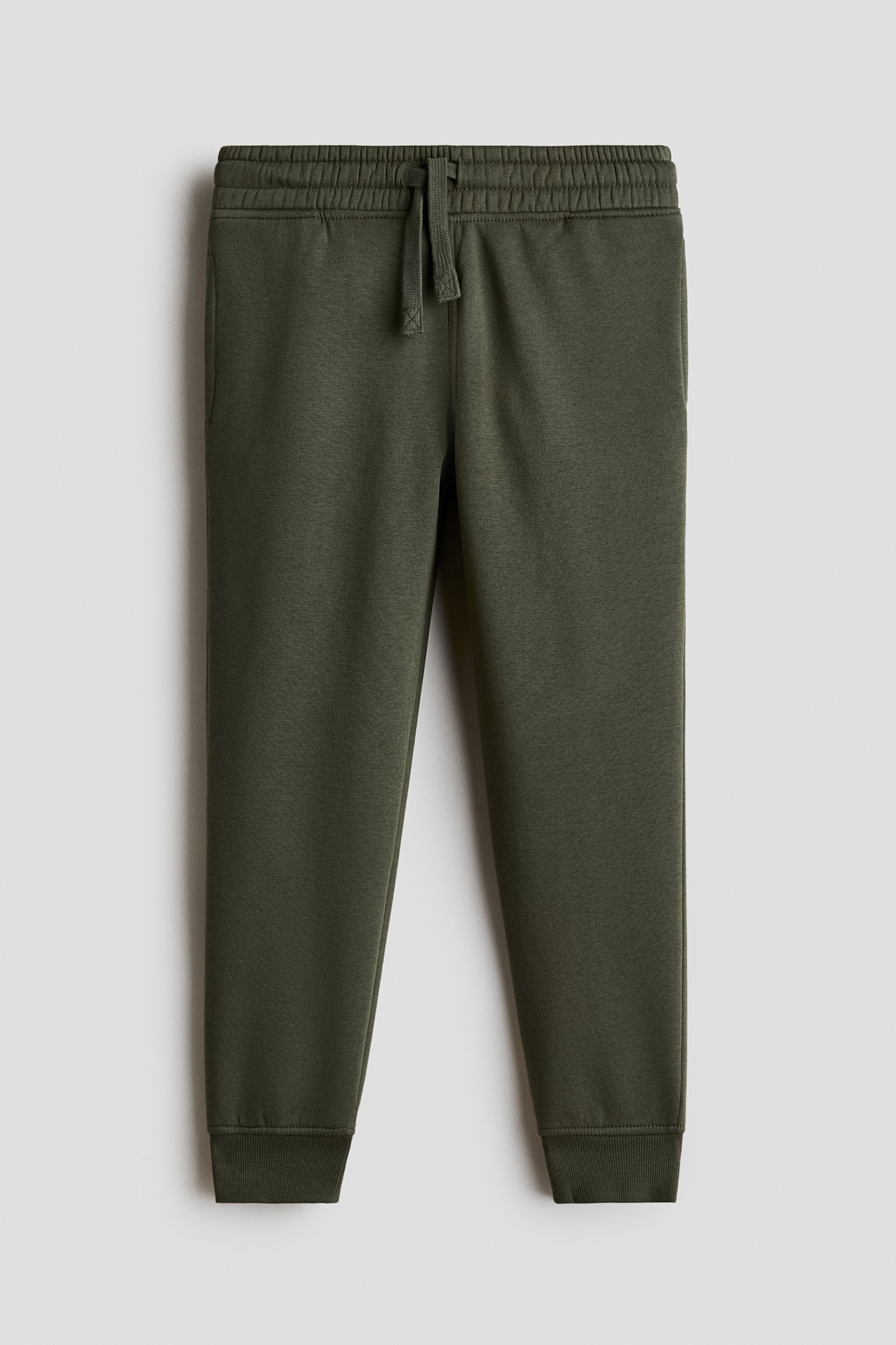 Dessa olivgröna joggingsbyxor visas framifrån och har en elastisk midja med justerbar dragsko. De har diskreta sidofickor och avsmalnande ben som avslutas med ribbade muddar.