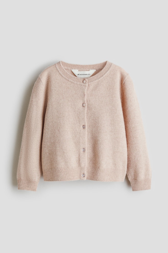 Un cardigan en maille fine rose clair est présenté de FACE, avec un col rond bordé de côtes, cinq boutons visibles descendant au centre devant, et des poignets et un ourlet bordés de côtes. - 1