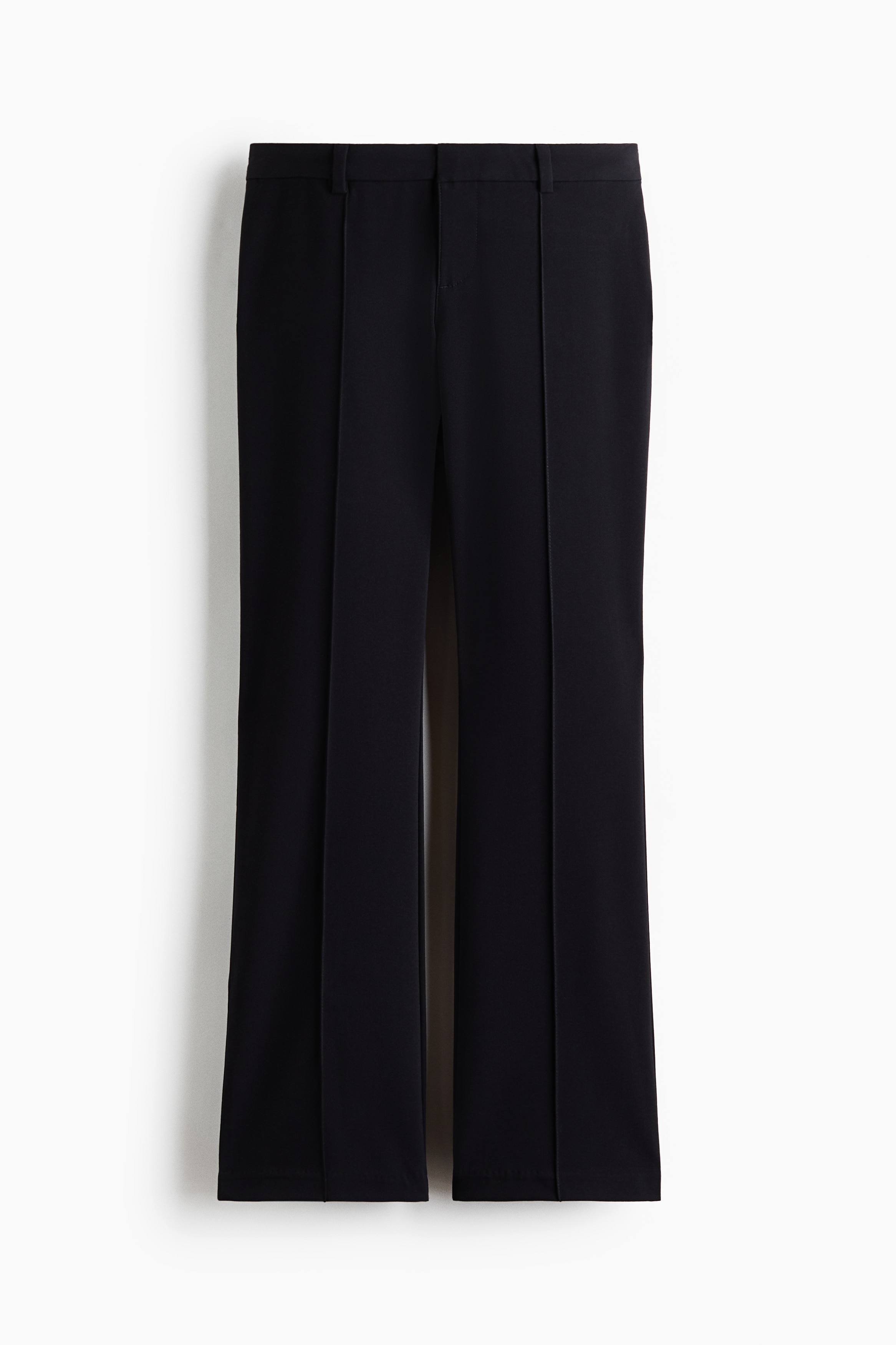 Model nosi crne pantalone uz prijanjanje, sa niskim strukom i bootcut nogavicama. Pantalone imaju izraÅ¾ene uÅ¡ivene pegle koje se spuÅ¡taju niz prednji deo svake nogavice i stilizovane su uz slojeviti top na bretele, crne sandale i crni Å¡eÅ¡ir od veÅ¡taÄkog krzna.