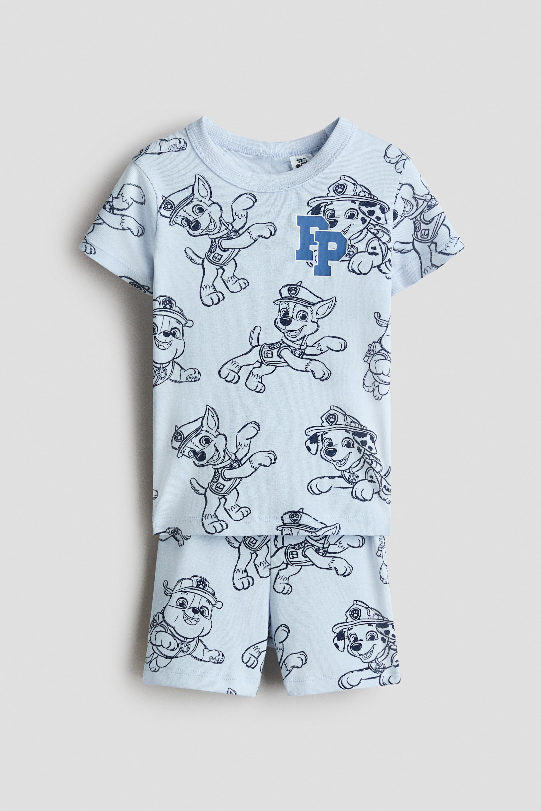View larger image: A light blue pajama t-shirt and shorts set, made of soft cotton jersey, is shown from the front. The short-sleeved t-shirt is featuring a round neckline and an allover dark blue print of cartoon dog characters, with a prominent 'FP' logo on the chest. The matching shorts are designed with an elasticated waist and are displaying the same print.