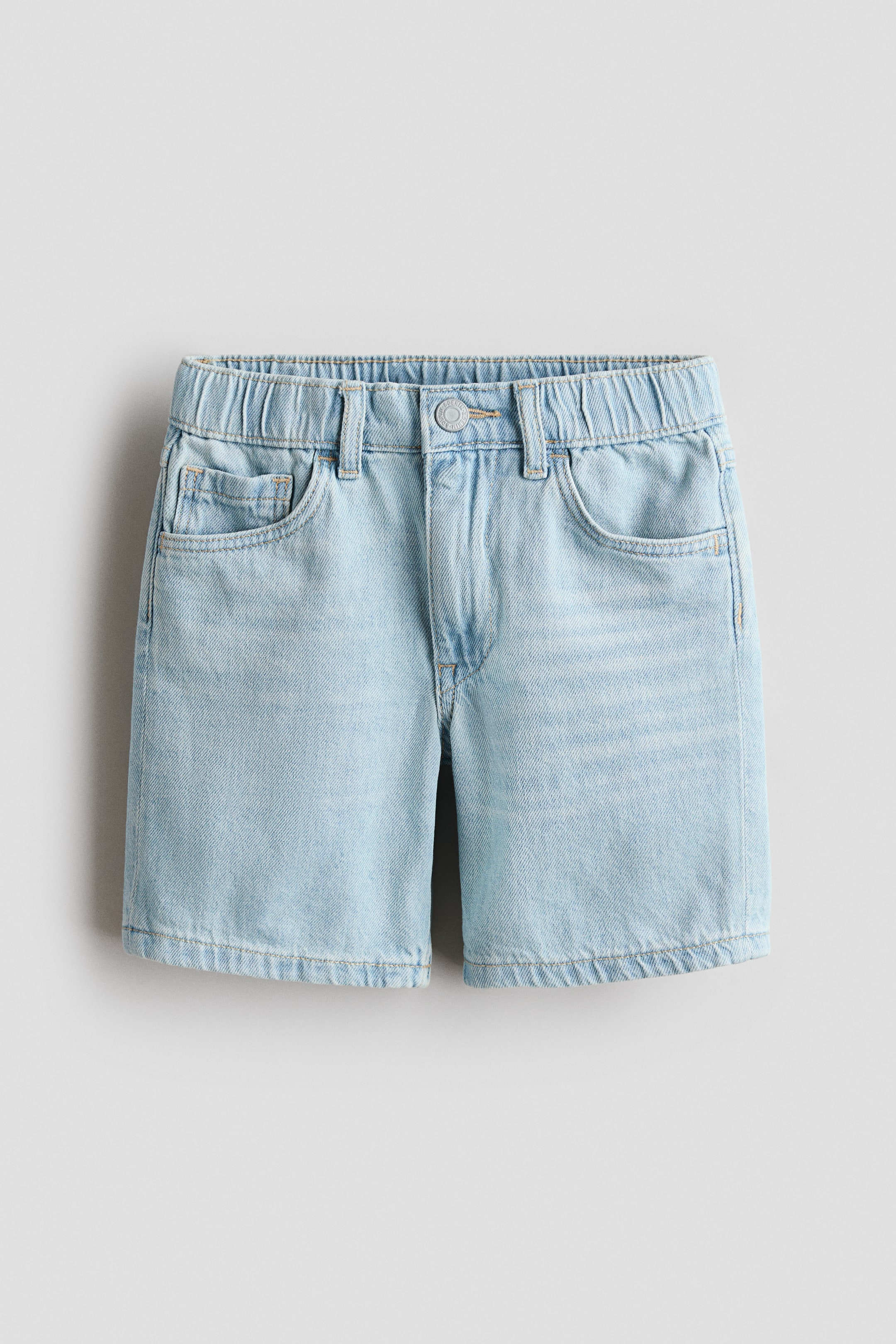 View larger image: Knee-length, 5-pocket shorts crafted from washed cotton denim are displayed from the front, showcasing an adjustable, elasticated waist and a zip fly with a press-stud fastening.