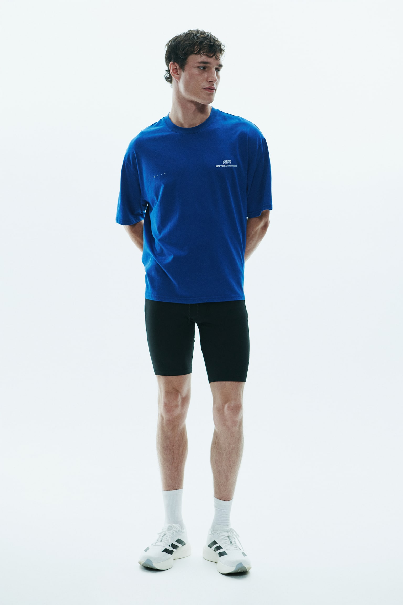A royal blue t-shirt is hanging facing front, featuring a crew neck, dropped shoulders, and relaxed short sleeves. The chest area displays small white printed details, including the word "MOVE" on the right side and "NYC NEW YORK CITY RUNNING" on the left side. - 1