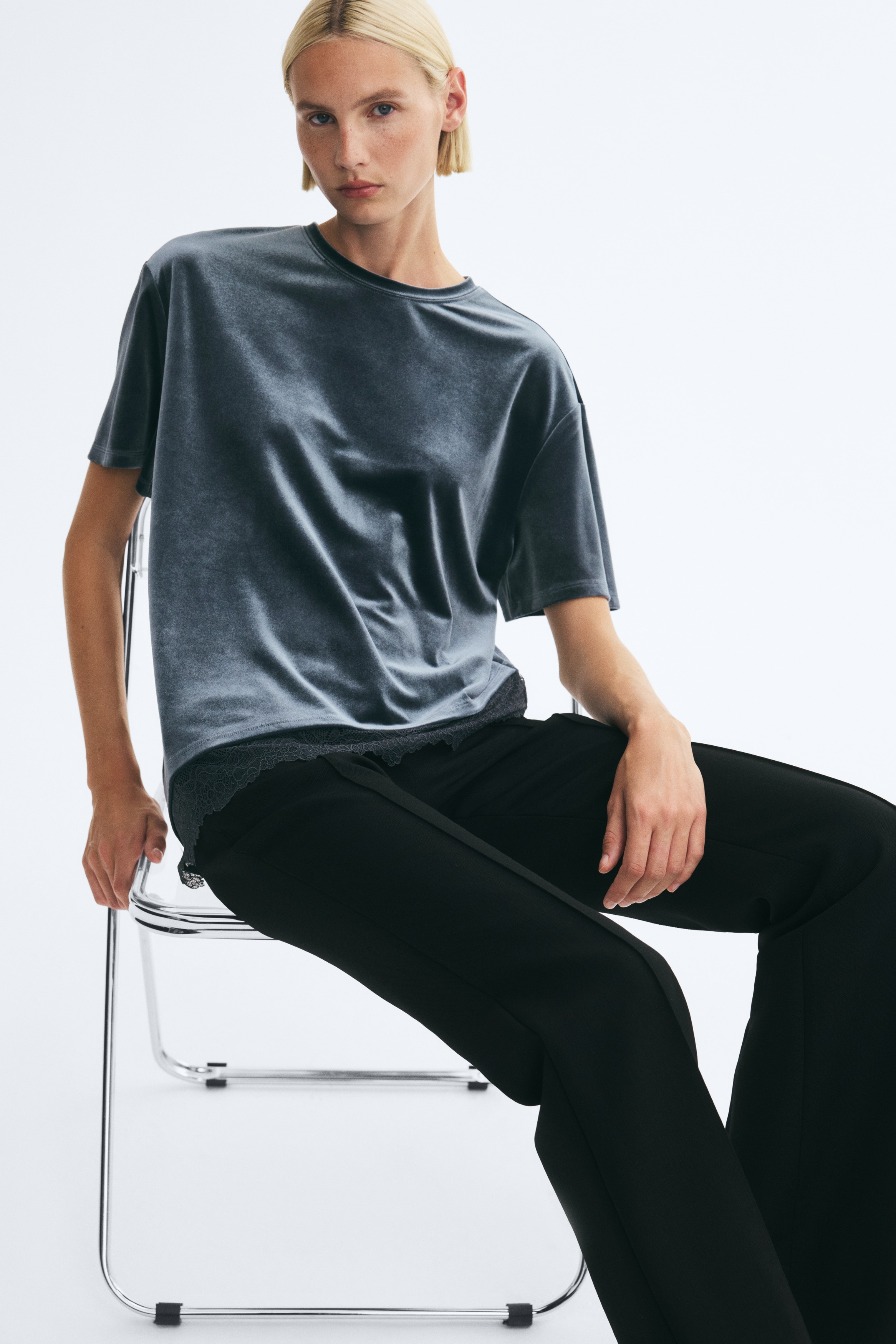 A dark teal velvet T-shirt is facing front, featuring a crew neck, loose short sleeves, and an asymmetrical hemline trimmed with delicate black lace.