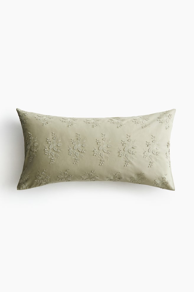 A light olive-green rectangular pillowcase is displaying intricate, tone-on-tone embroidered floral patterns across its front surface. - 1