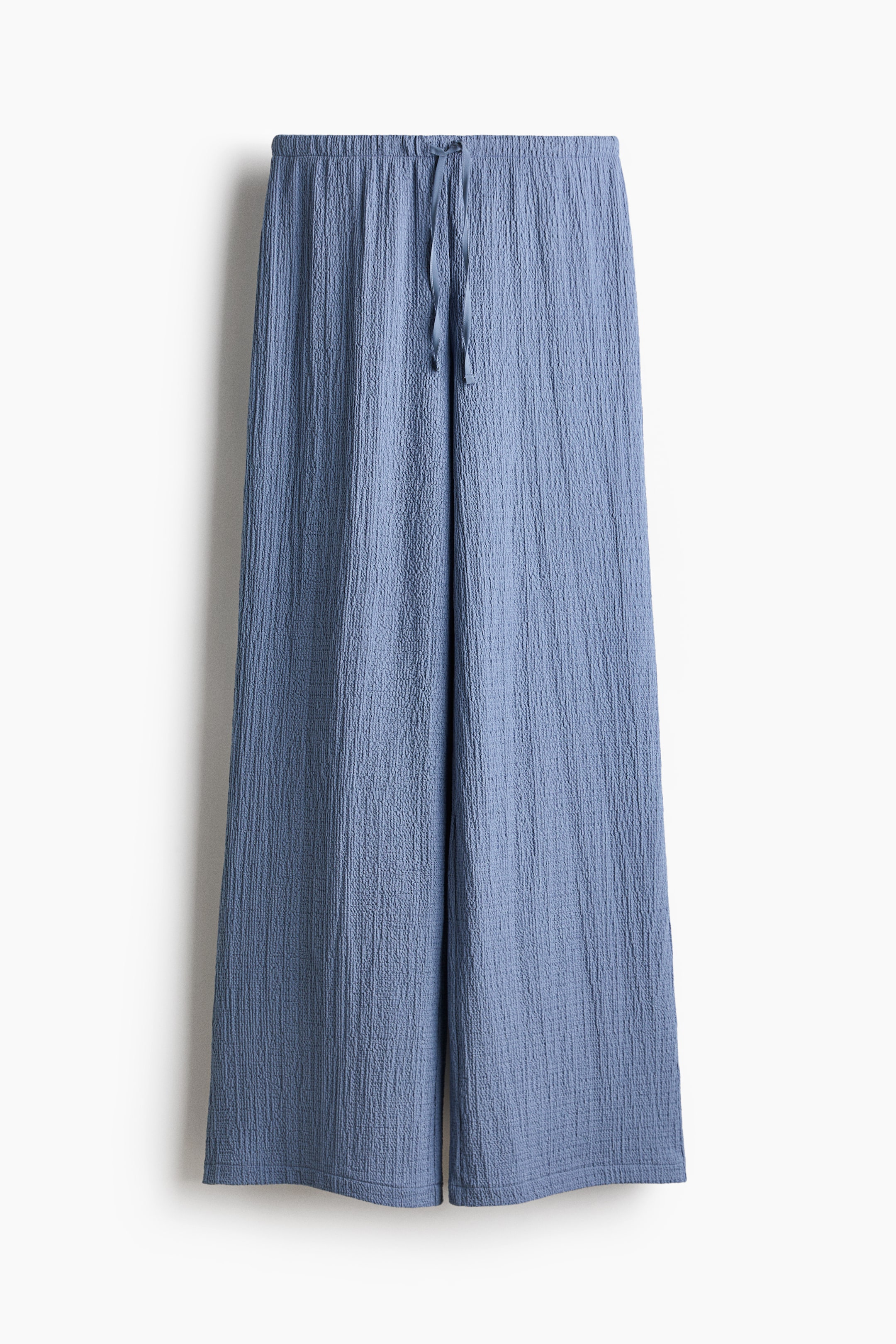 View larger image: The blue textured jersey trousers are showcased from the front, highlighting an elasticated, drawstring waist with the drawstring visibly tied, and displaying straight legs.
