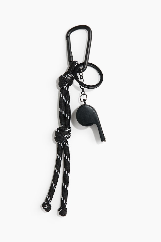 Un bijou de sac présente un mousqueton noir à son sommet. Une corde noire, affichant des motifs en zigzag blancs et deux nœuds visibles, descend du mousqueton. Un pendentif en forme de sifflet noir pend également à un porte-clés, qui se connecte au mousqueton via une petite chaîne noire. - 1
