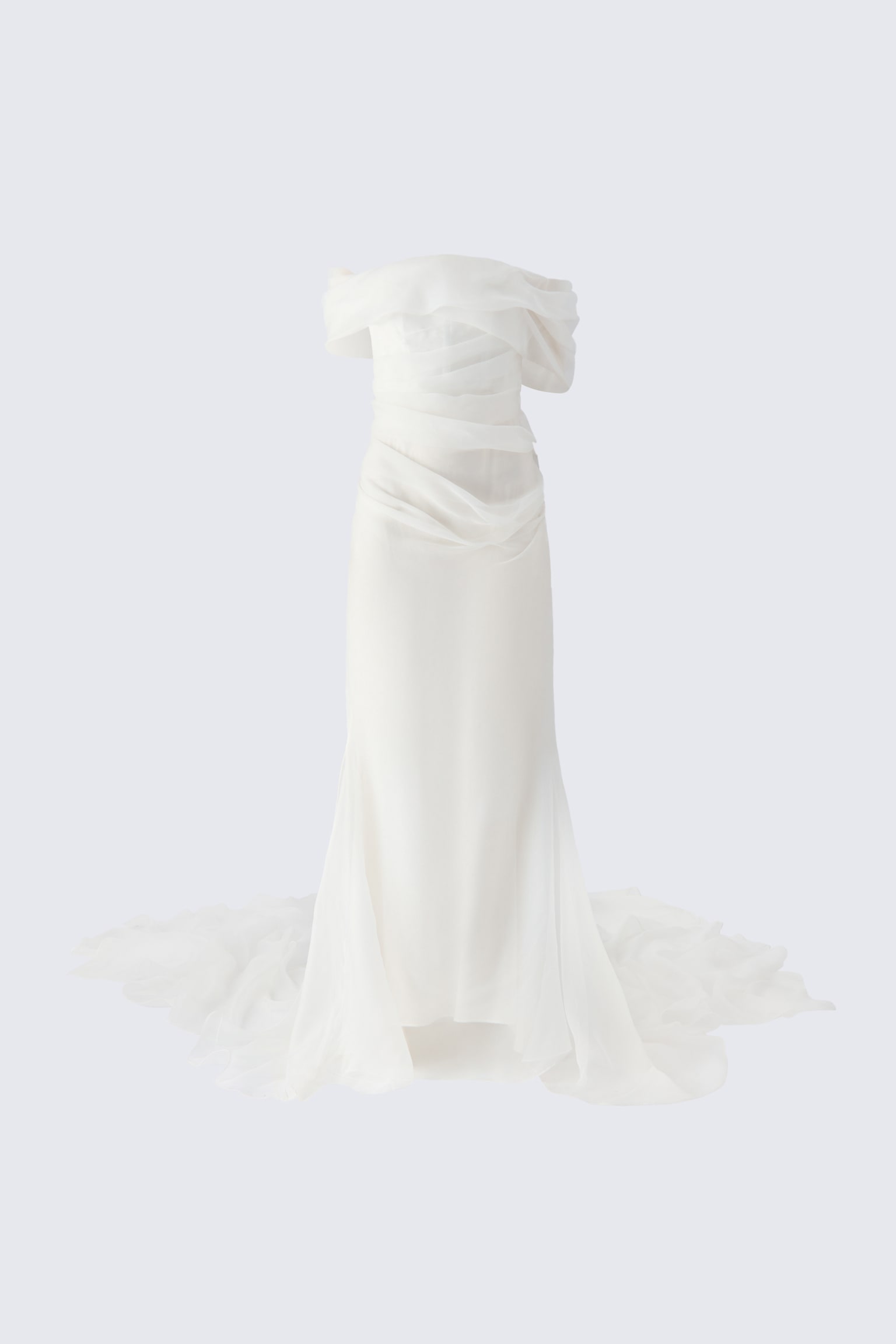Un vestido de novia tipo bandeau de color marfil aparece de frente, mostrando un adorno voluminoso y drapeado de hombros descubiertos y un cuerpo de organza envolvente con pliegues. La silueta ajustada se ensancha en la parte inferior en una falda estilo sirena con una cola espectacular y con volantes que se extiende por el suelo.