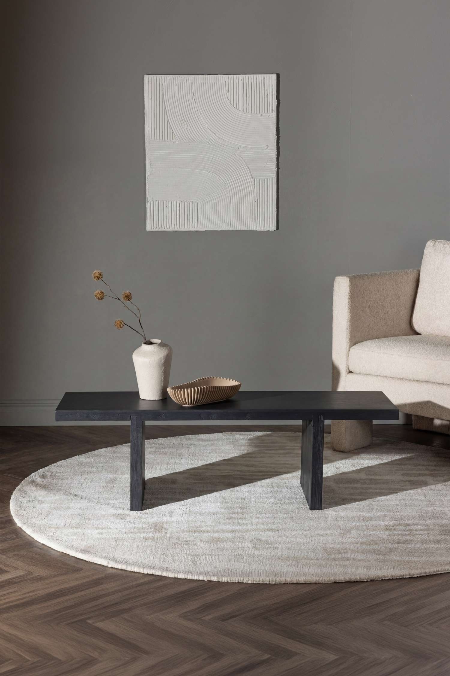 Un banco largo de madera tintada en tono oscuro se muestra de frente, con una tapa gruesa rectangular sostenida por dos patas anchas y rectangulares en forma de bloque, con uniones encajadas visibles.