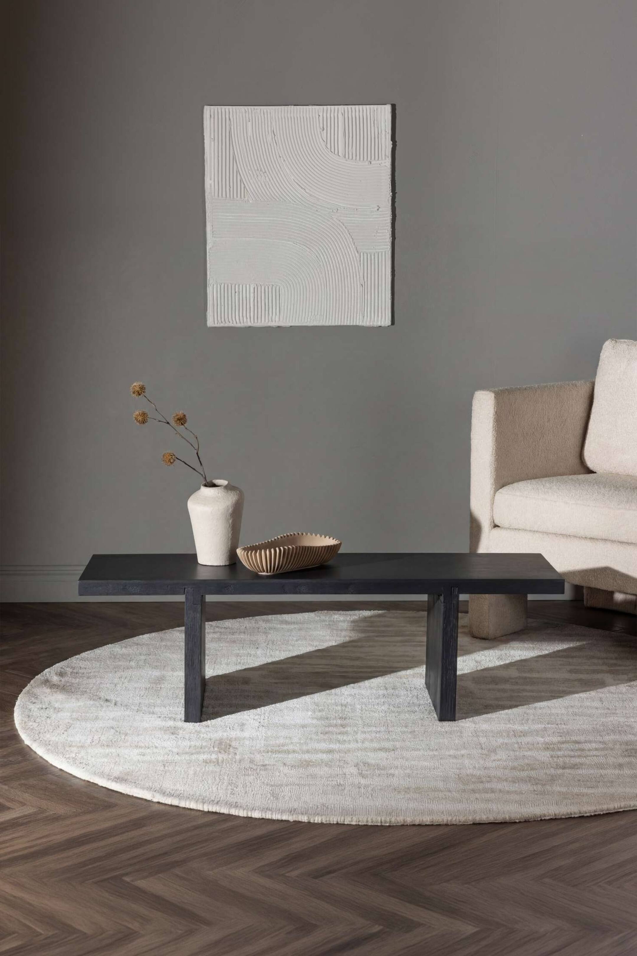 Ver imagen más grande: Una mesa de centro rectangular de madera negra se apoya sobre dos gruesas patas de losa empotradas, mostrando un diseño minimalista con un tablero plano y texturizado.