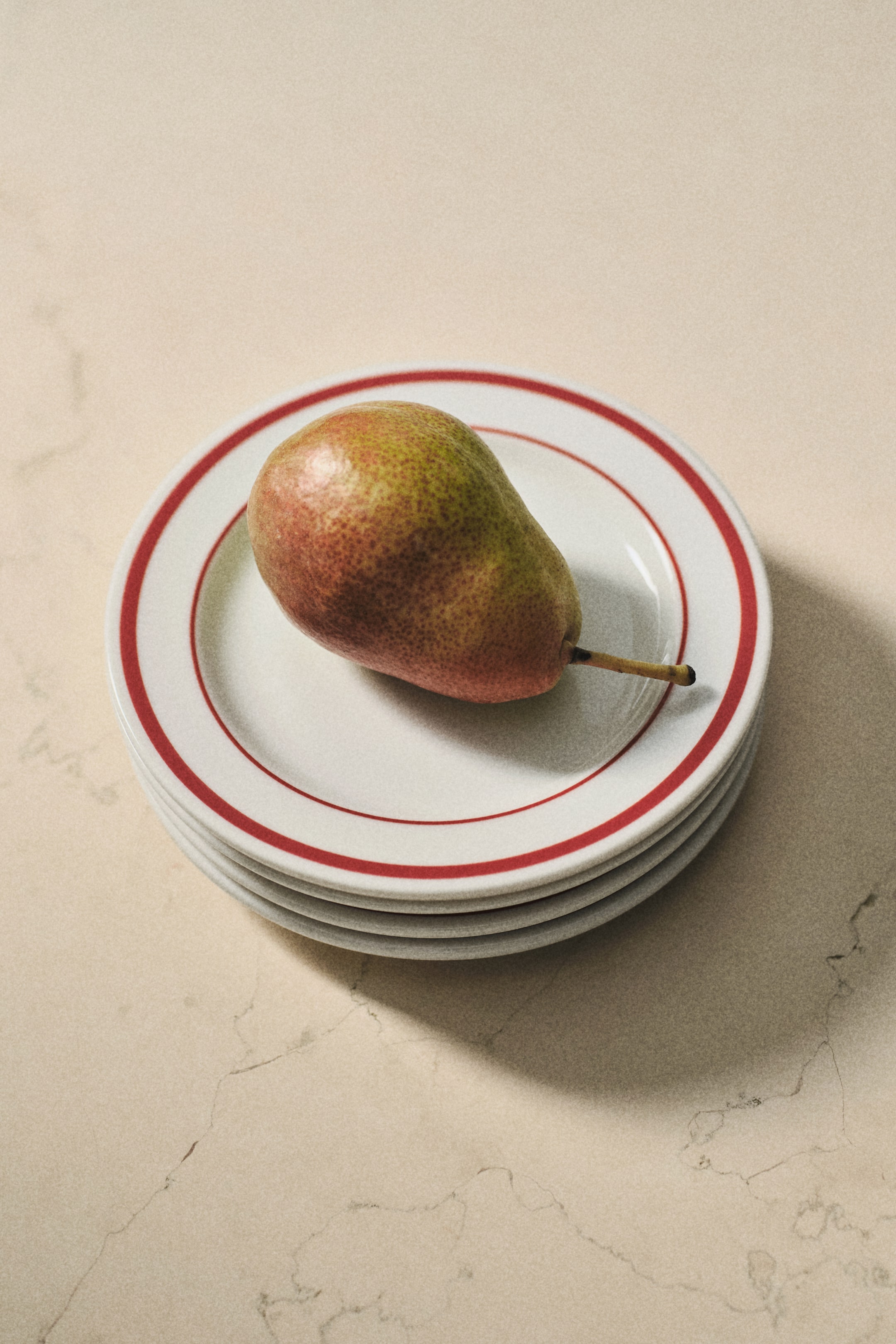 View larger image: A stack of four white porcelain side plates is shown, each featuring a classic red painted rim.