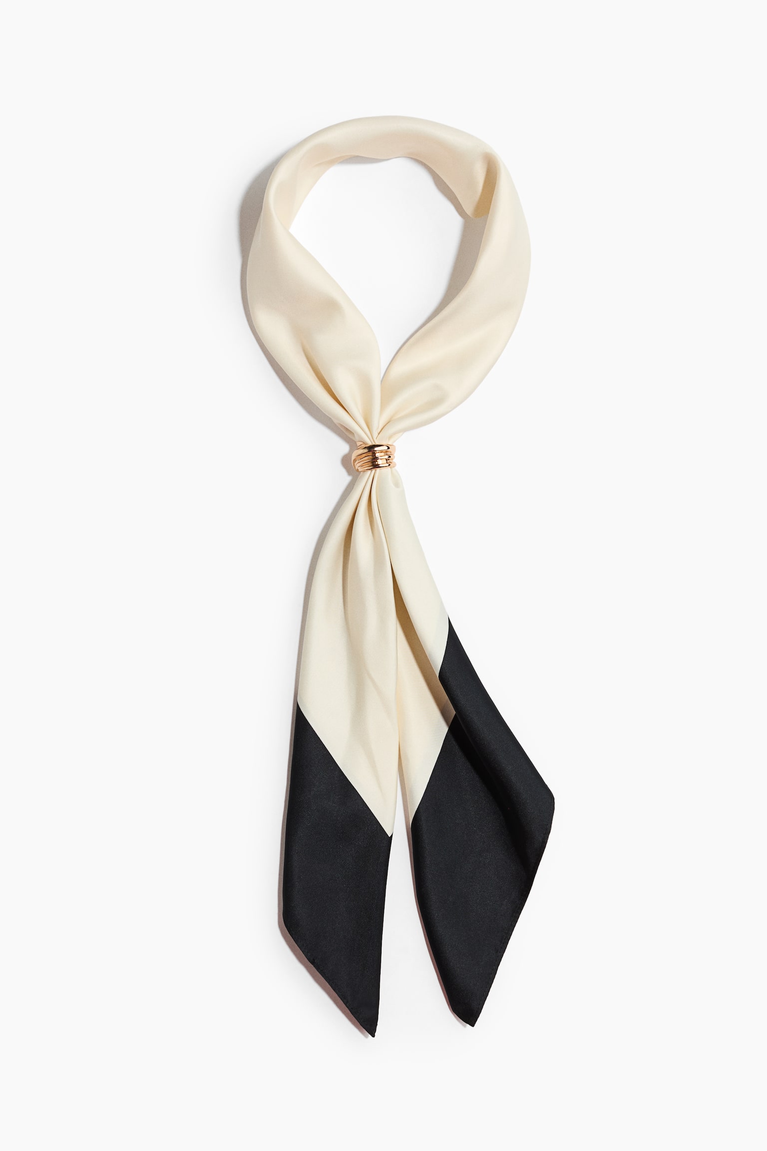 A square neck scarf in a woven fabric is displayed from the front, featuring a colour-blocked design with a cream upper loop and black pointed ends. A gold-toned, ribbed metal ring secures the gathered fabric at the centre, allowing the two ends to drape downwards.