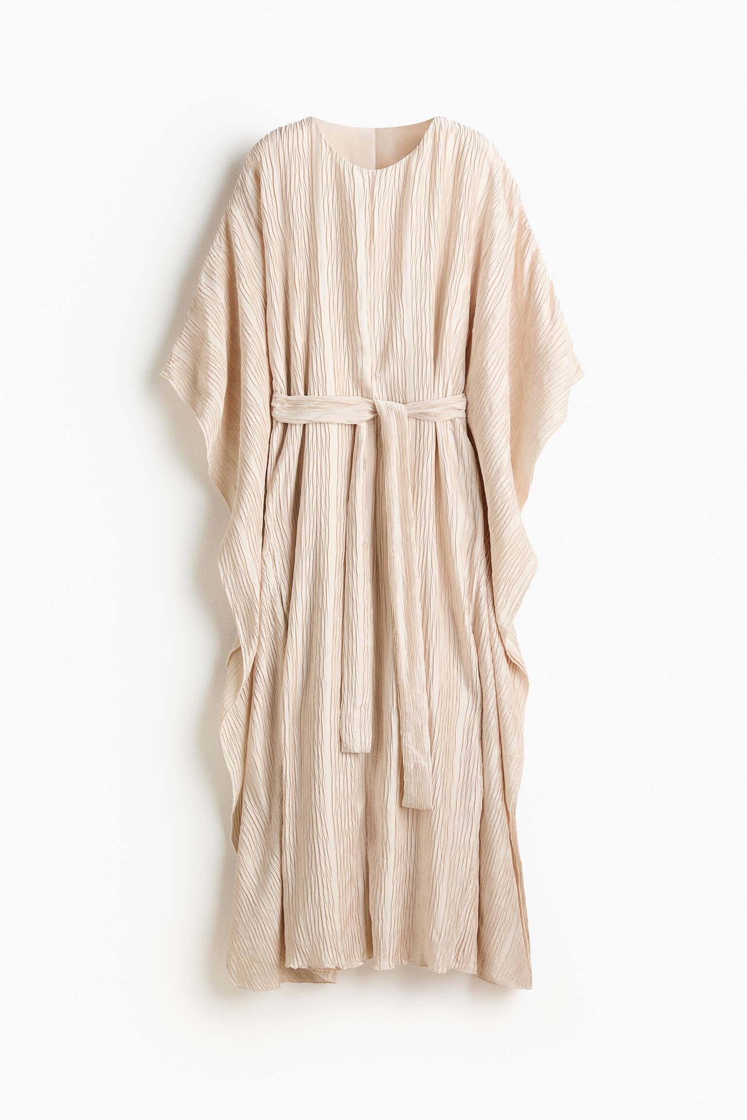 A cream kaftan dress is featuring an all-over crinkled texture, presenting its FRONT. A matching self-tie belt is cinching the waist, creating soft gathers, and wide, integrated sleeves are draping from the shoulders. - 1