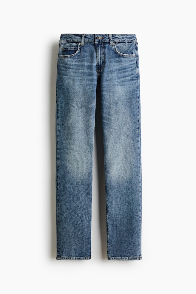 Se muestra un par de vaqueros de denim azul desde el frente, con una silueta de pernera recta y el clÃ¡sico diseÃ±o de cinco bolsillos. El denim de lavado medio presenta un sutil desgastado y marcas de desgaste en los muslos y las caderas, con cierre de botÃ³n y trabillas para cinturÃ³n en la cintura. - 1