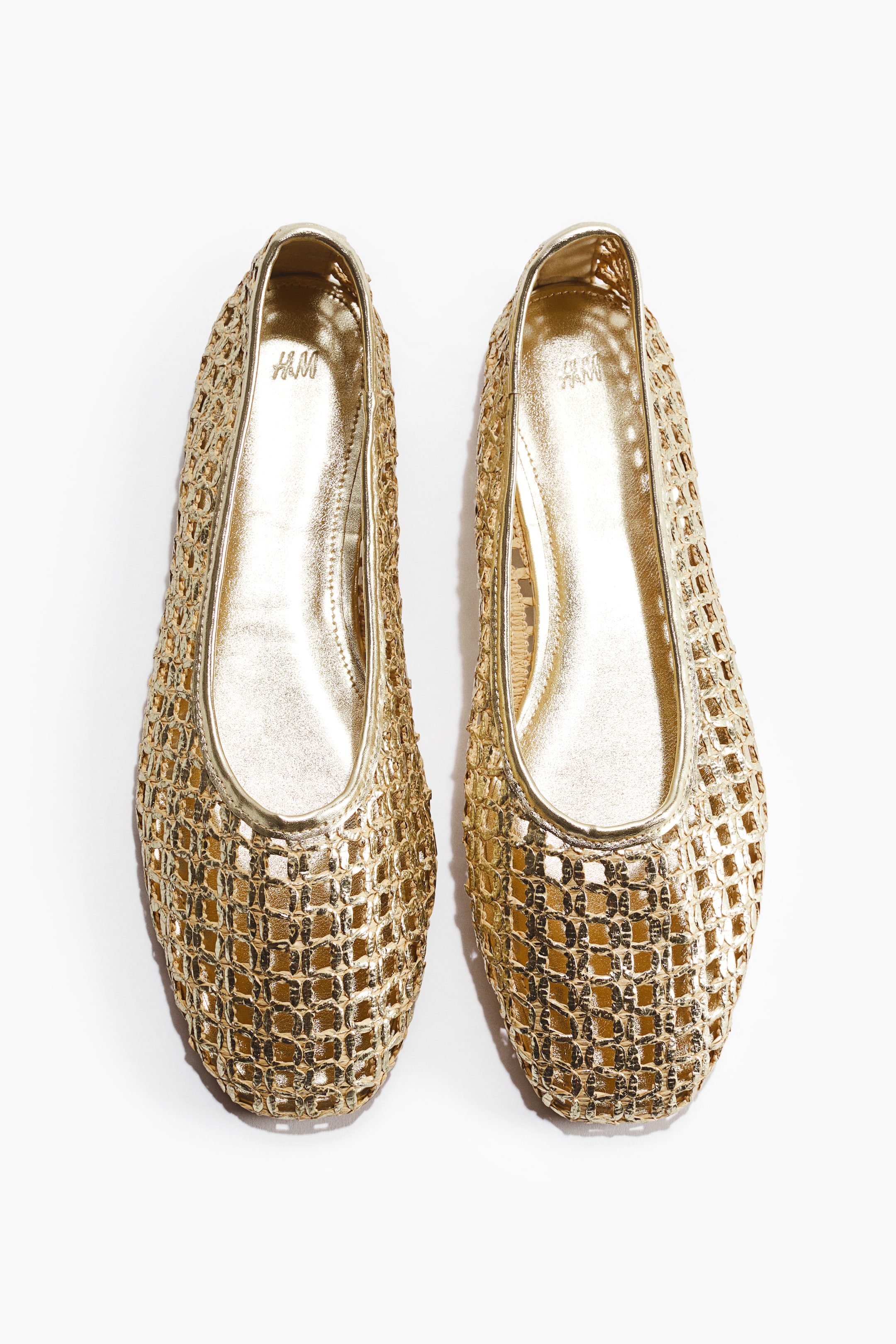 View larger image: Gold ballet flats showcase a woven gold plastic straw design, captured from the front. They boast square toes and a slender gold trim outlining the opening.
