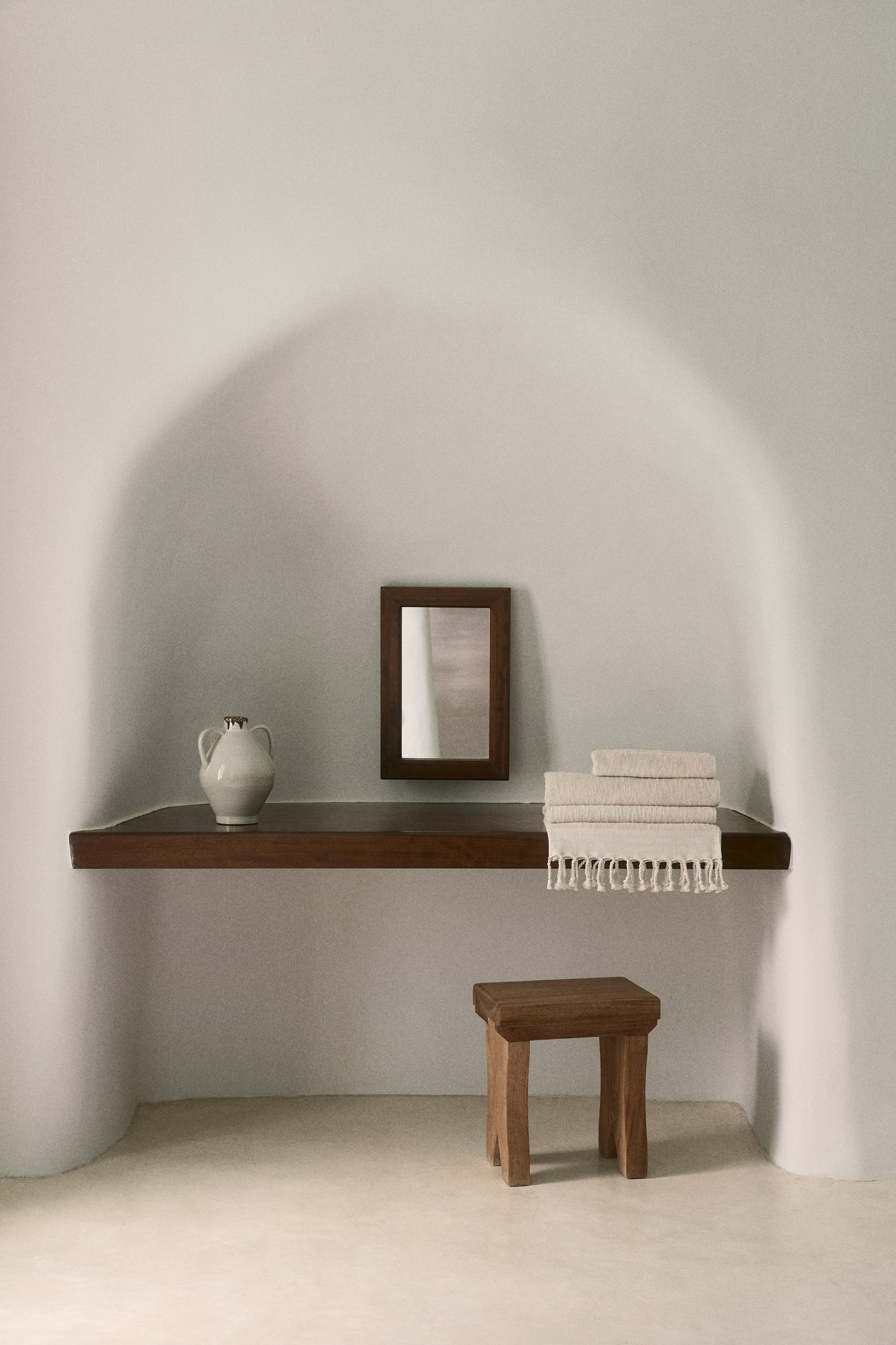 View larger image: The wooden stool boasts a rich dark brown finish and a rectangular seat, supported by four sturdy, angled legs, and is showcased from a front-left three-quarter perspective.