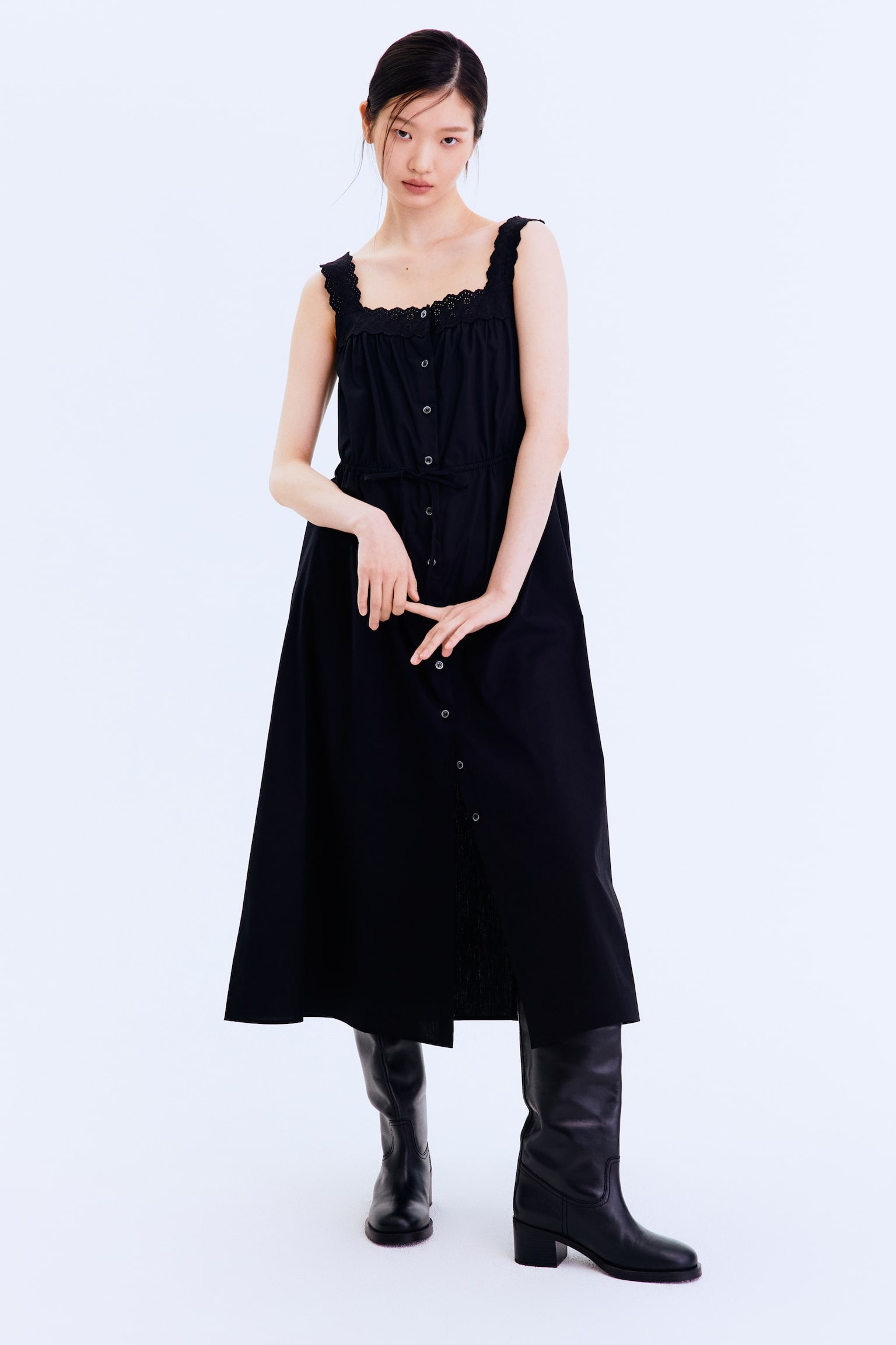 "A black midi dress featuring a square neckline with scalloped trim along the neckline and straps. Designed with a full button-front closure and a drawstring waist, creating a flowing A-line silhouette." - 1