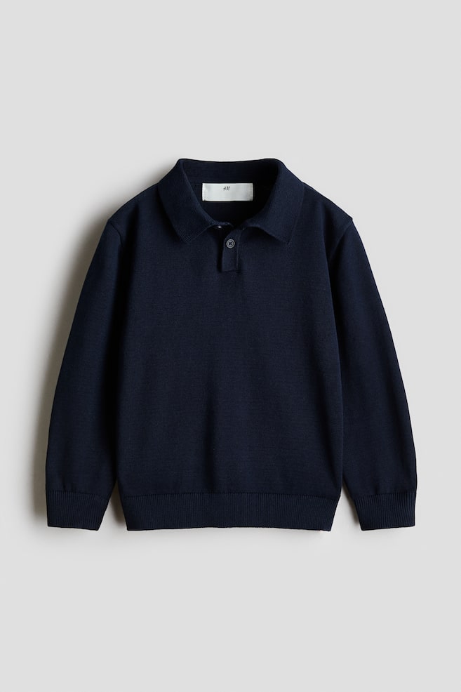 A dark blue long-sleeve polo jumper is shown from the front, featuring a fine-knit cotton fabric, a classic collar, and a short button placket. Ribbed detailing finishes the cuffs and hem. - 1