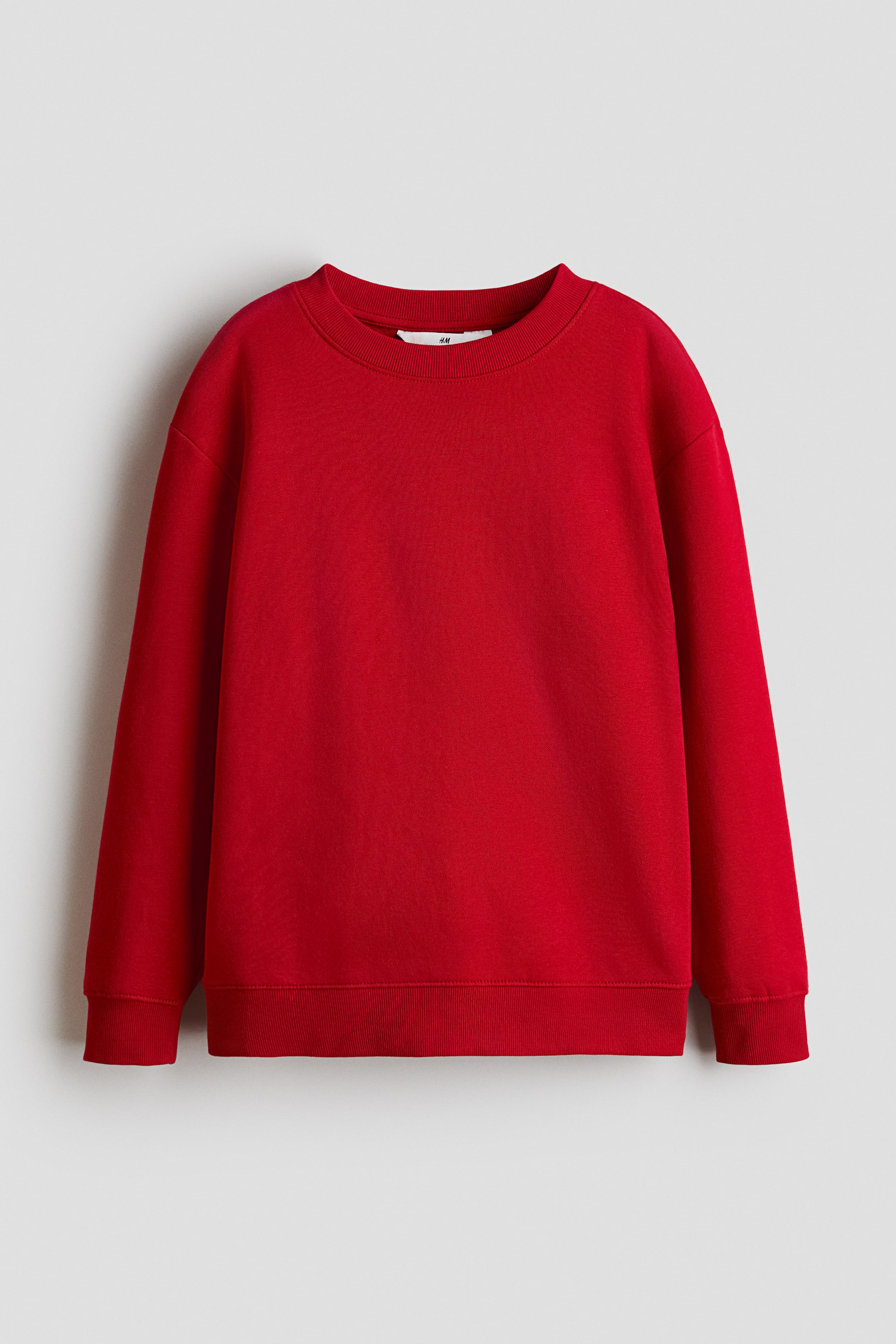 Größeres Bild ansehen: Ein roter Sweatshirt wird von vorne präsentiert und verfügt über einen rund gerippten Ausschnitt, überschnittene Schultern und lange Ärmel. An den Bündchen und am Saum ist Rippenstruktur sichtbar.