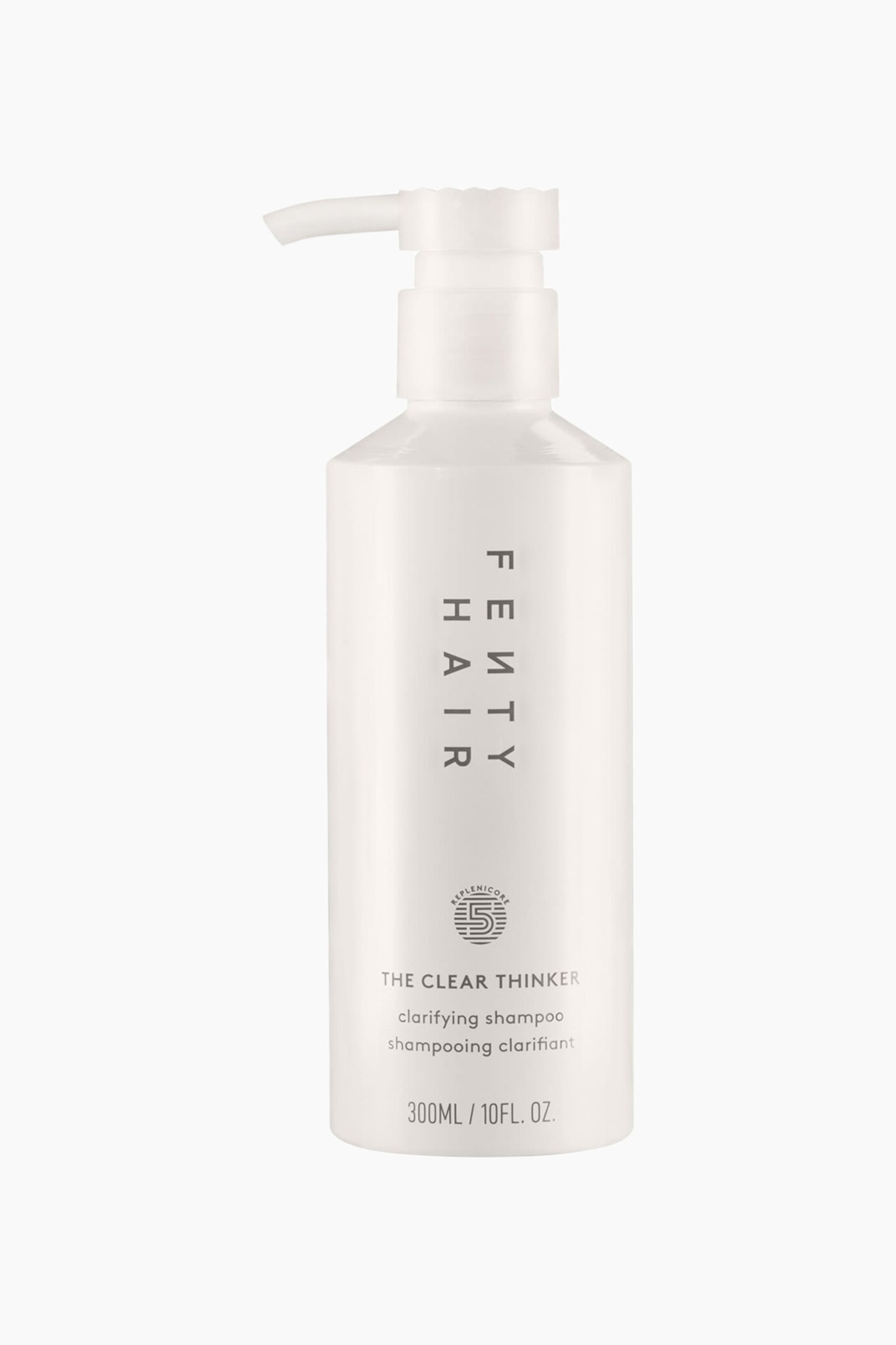 En cylindrisk benvit flaska med Fenty Hair "The Clear Thinker" djuprengÃ¶rande schampo stÃ¥r upprÃ¤tt, med en matchande pumpdispenser som Ã¤r riktad Ã¥t vÃ¤nster. Flaskan har vertikal grÃ¥ varumÃ¤rkestext fÃ¶r "FENTY HAIR" pÃ¥ framsidan, ovanfÃ¶r en cirkelformad "Replenicore 5"-logotyp och produktinformation.