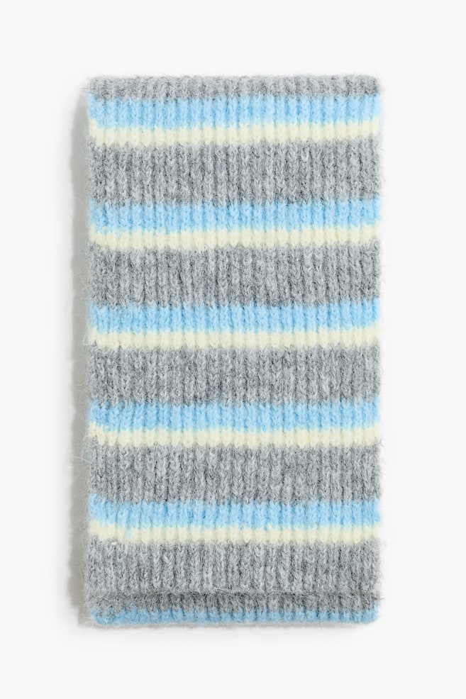 Una bufanda larga de punto acanalado suave y afelpado está extendida en plano y orientada de frente, mostrando un estampado de rayas horizontales en gris, azul claro y amarillo pálido. - 1