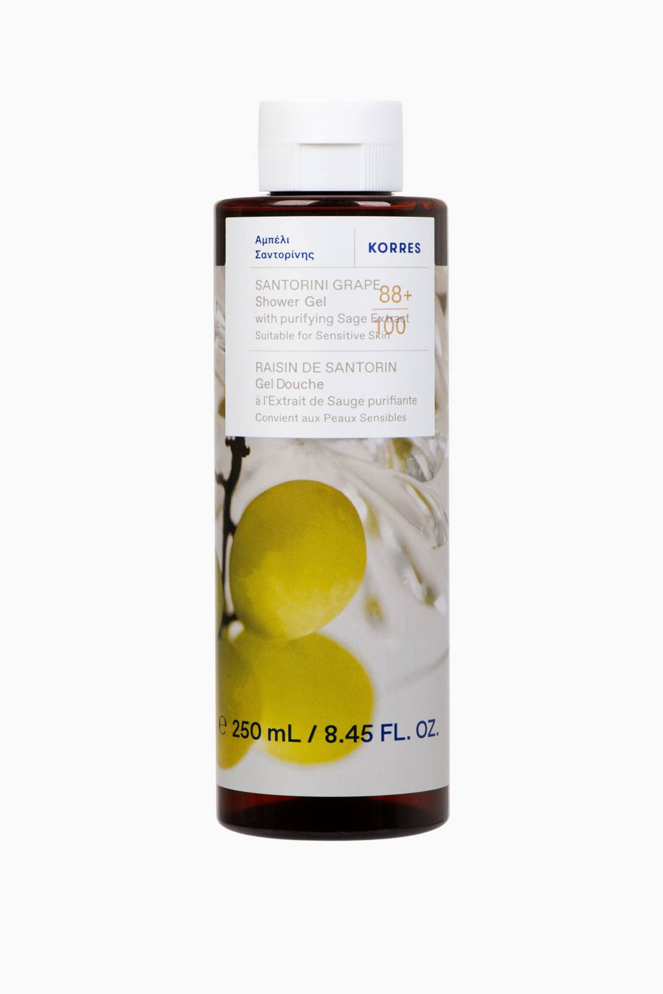 Visa större bild: En mörkbrun genomskinlig cylindrisk flaska med Santorini Grape Shower Gel står upprätt, vänd framåt. En vit rektangulär etikett omsluter flaskan, visar en bild av gröna druvor och produktinformation, toppad med ett vitt flip-top lock.