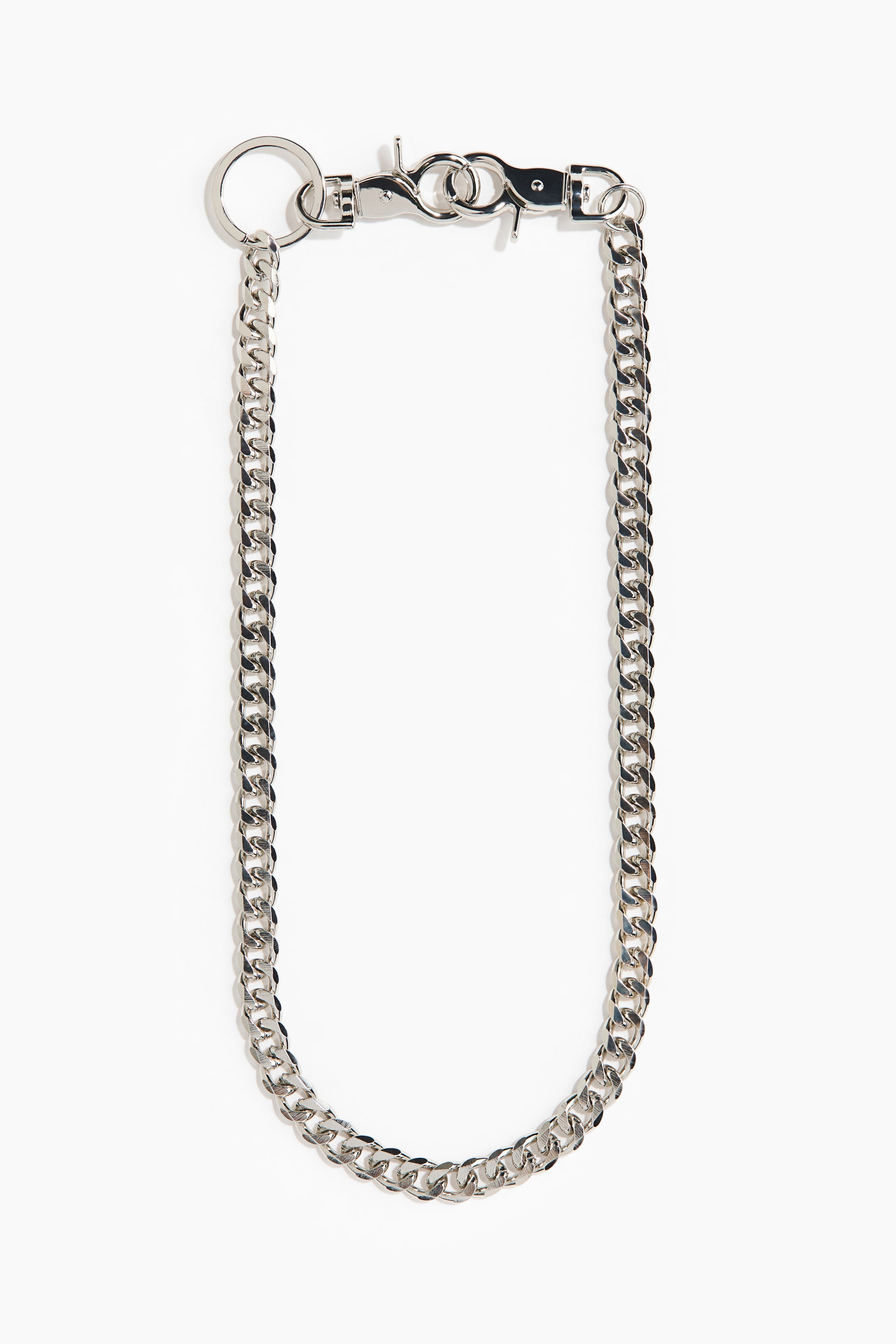 Büyük resmi görüntüle: Gümüş tonlu bir curb zincir, bir u şeklinde sunulmakta olup, bir ucunda dairesel bir anahtarlık halkası ve diğer ucunda dikdörtgen bir bara bağlı iki ıstakoz klipsi bulunmaktadır.