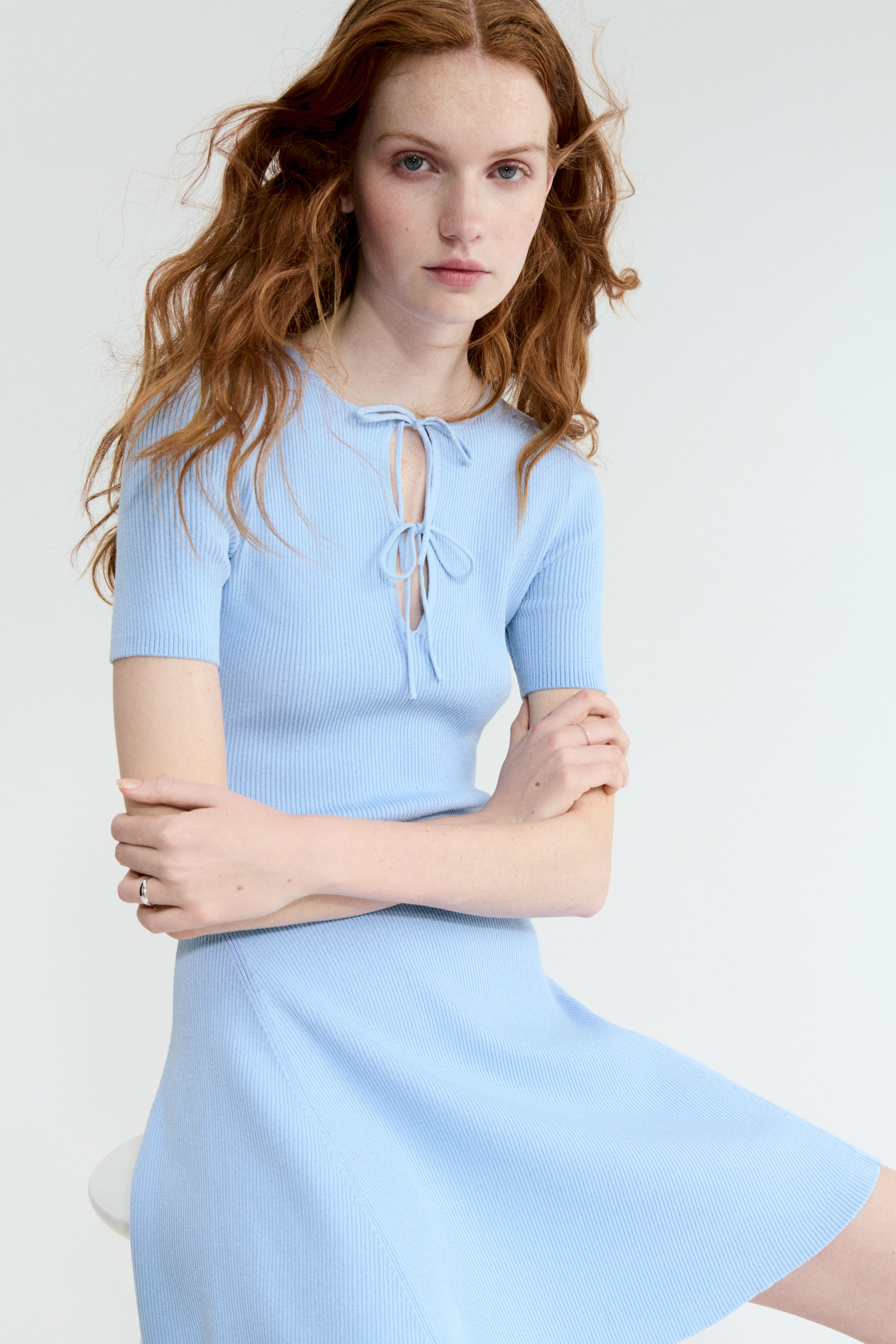 Agrandir l'image: La robe en maille côtelée bleu clair présente des manches courtes et un col rond avec une découpe en goutte d'eau sécurisée par des liens. Son côtelage vertical façonne un buste ajusté et une jupe évasée.