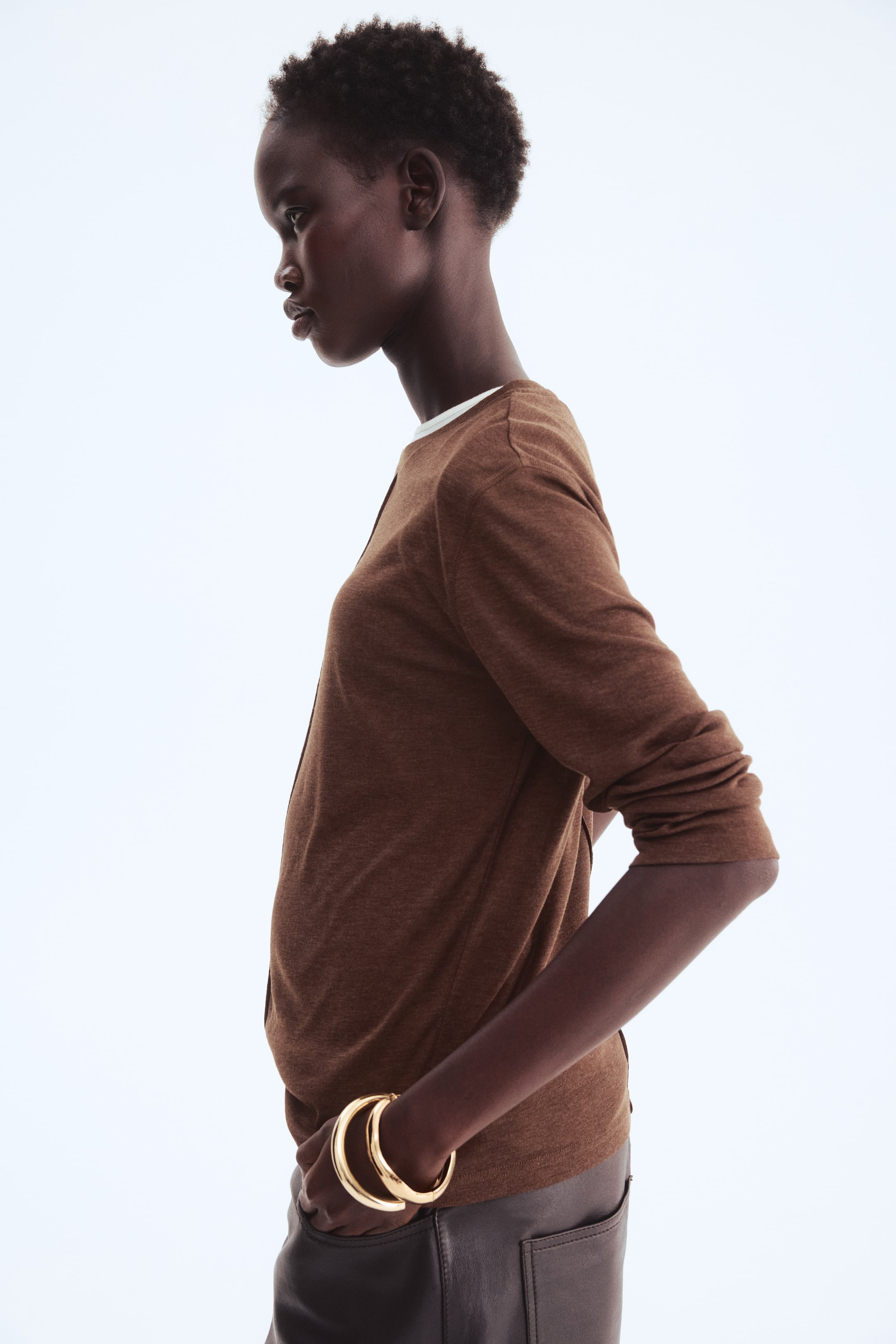 View larger image: A heathered brown long-sleeve cardigan is displayed facing slightly to the left, featuring a round neckline and an open front, revealing a white layer underneath.