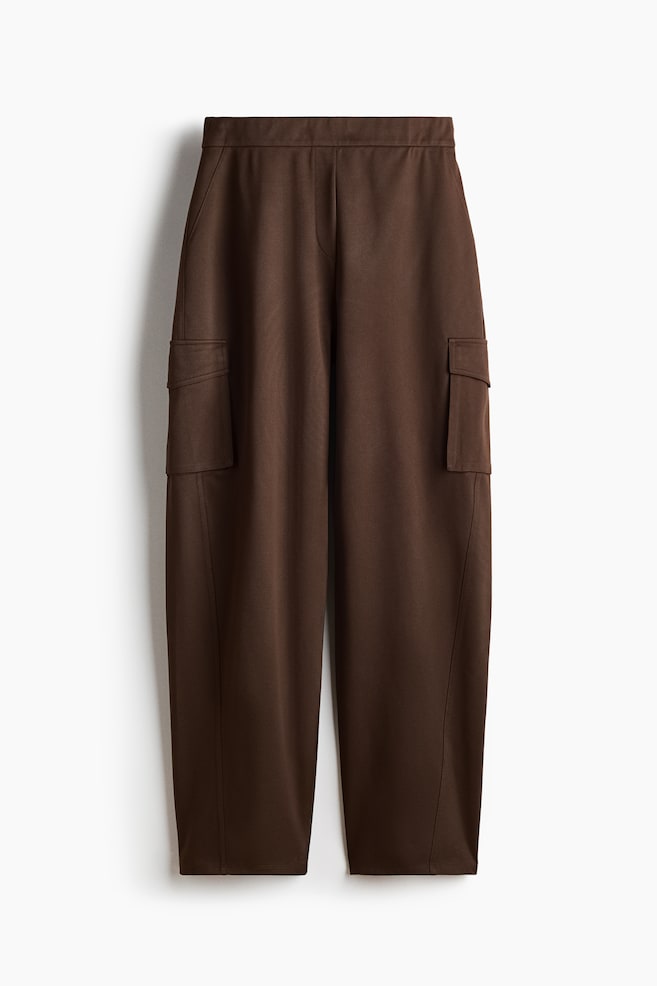 Brown cargo pants featuring a flat waistband, two hip pockets, and two large flap cargo pockets on the outer sides of the legs. The pants boast a relaxed, straight-leg cut. - 1